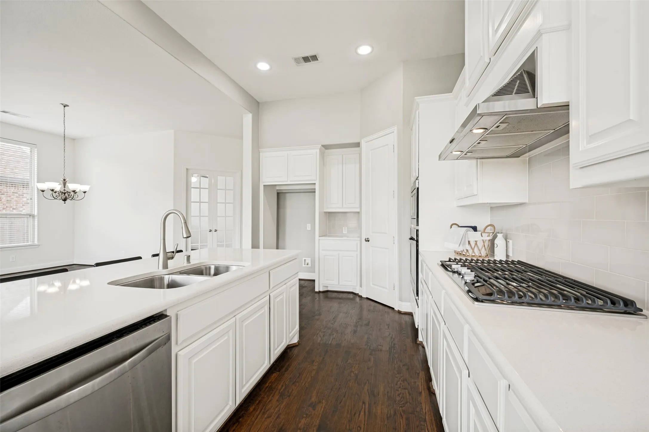 White kitchen light and bright with stainless appliances and gas cooktop