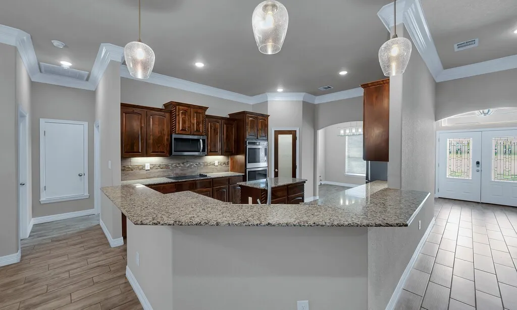 Kitchen with wood-finish cabinetry, built-in stainless steel appliances, and a breakfast bar with stone countertops