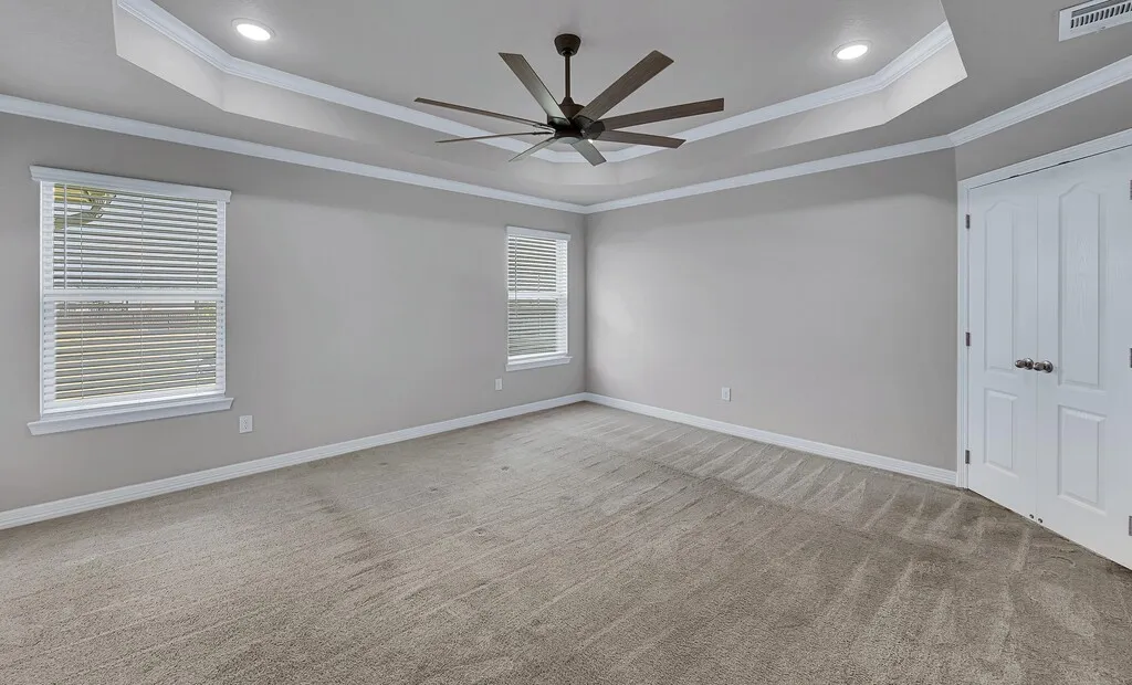 Tray ceiling with recessed lighting, ceiling fan, and crown molding