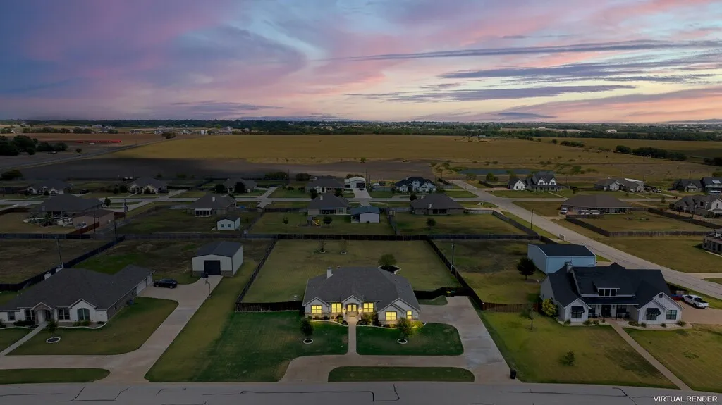 Aerial overview of a residential neighborhood with single-story homes and a large surrounding field