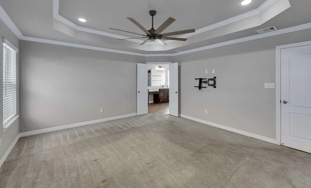 Tray ceiling with crown molding, recessed lighting, and a ceiling fan