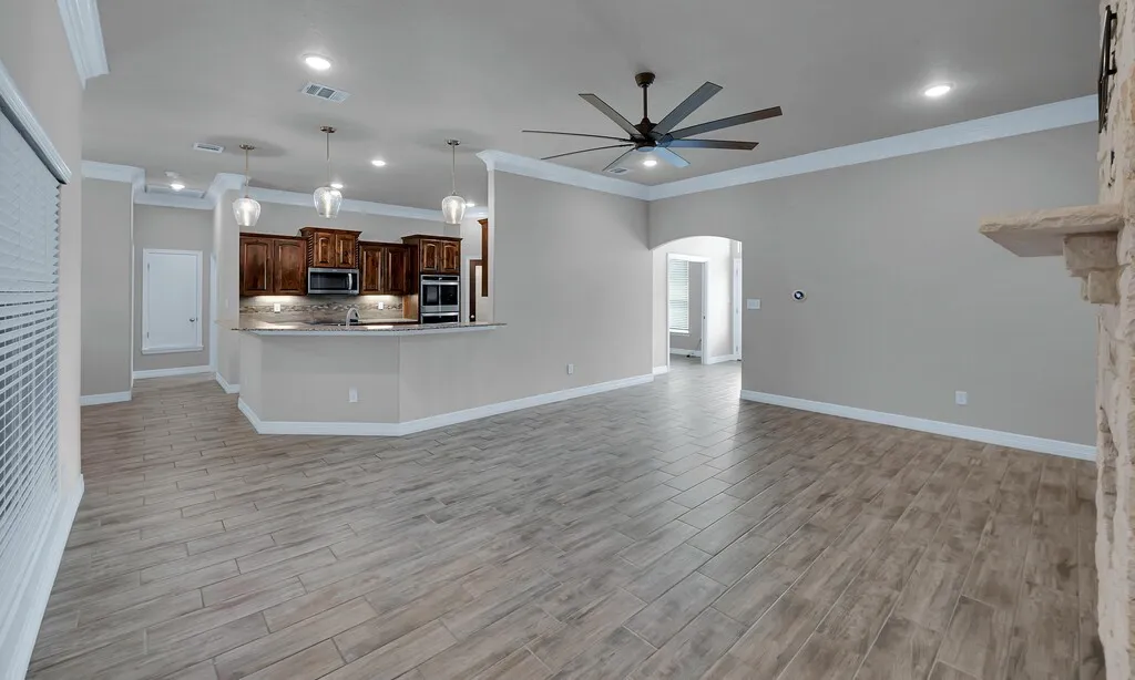 Open-concept living area with wood-look tile flooring, crown molding, and recessed lighting