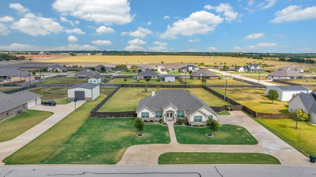 Expansive property featuring a spacious concrete driveway, established fencing, and a detached metal storage building