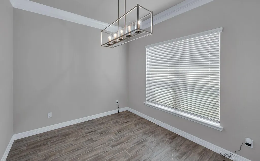 Wood-finish flooring, crown molding, white baseboards, and a modern rectangular chandelier