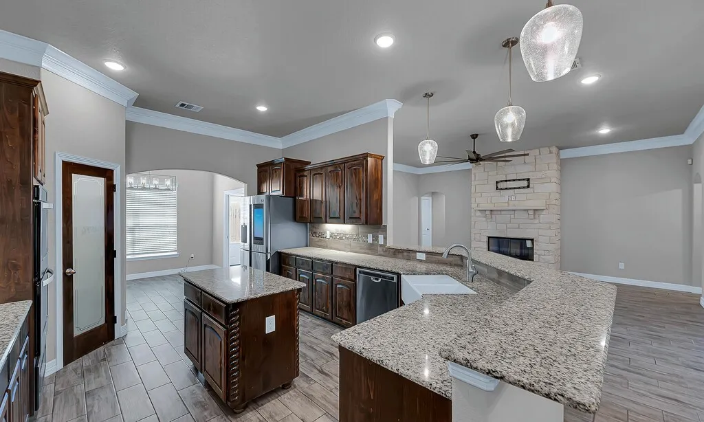 Kitchen featuring an island, granite countertops, dark wood cabinetry, and stainless steel appliances