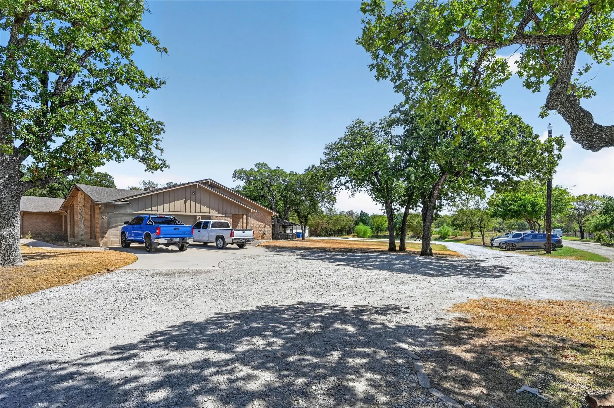 Property setting with mature trees, spacious driveway, and existing residence.