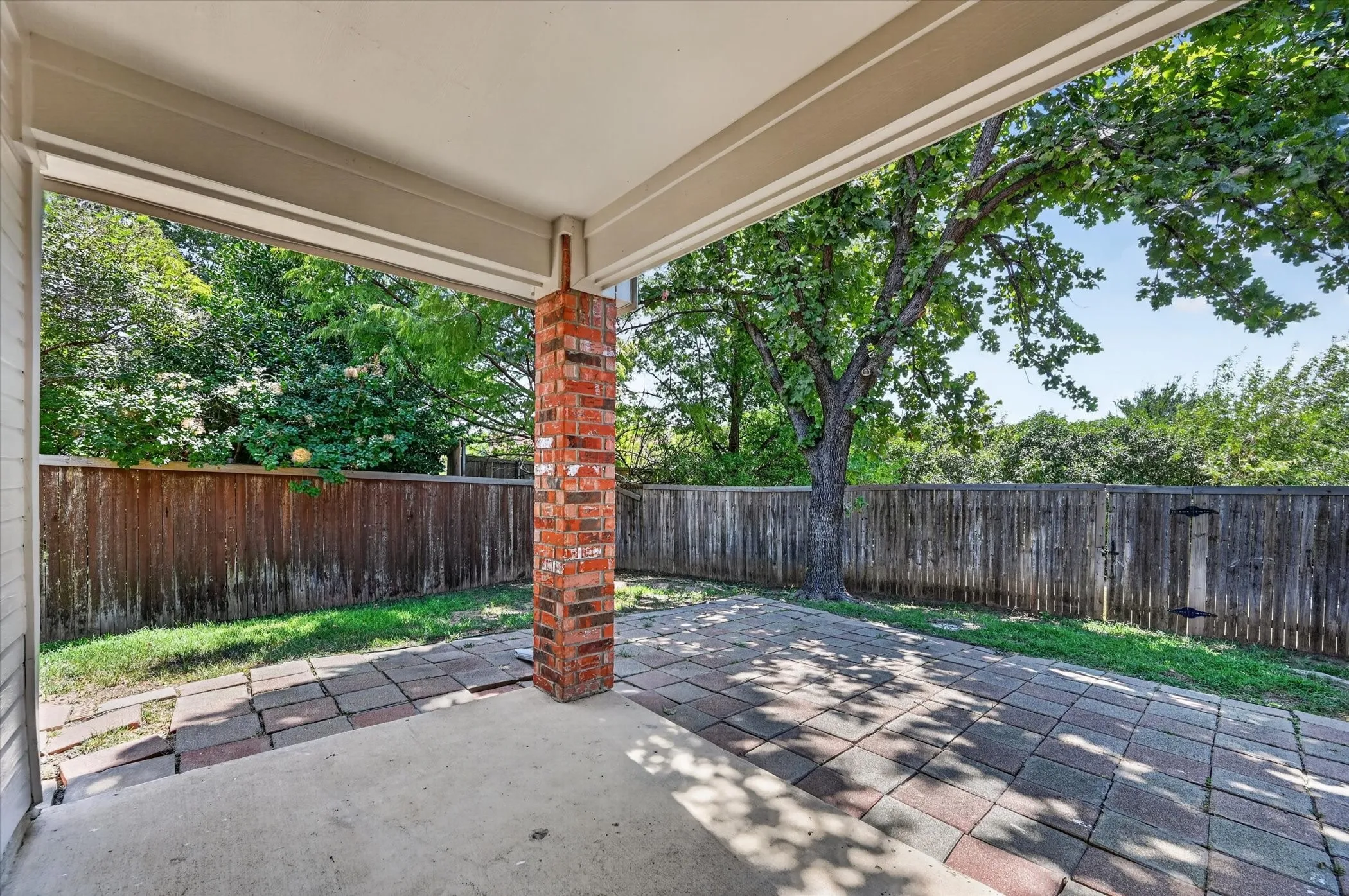Covered patio with brick column, concrete pad, and paver stone extension