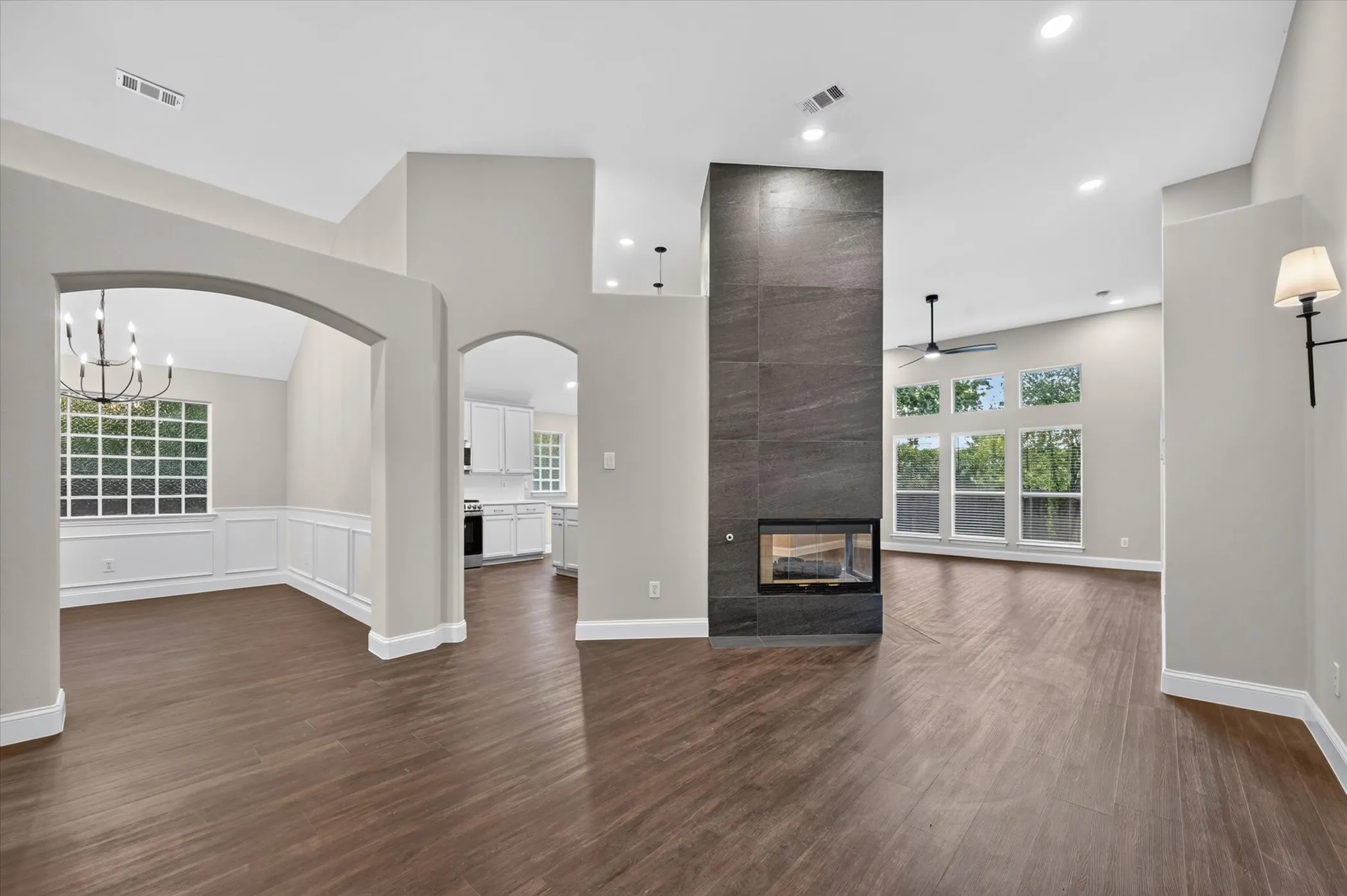 Spacious interior featuring wood-finish flooring, vaulted ceilings, and a modern fireplace with a dark stone surround