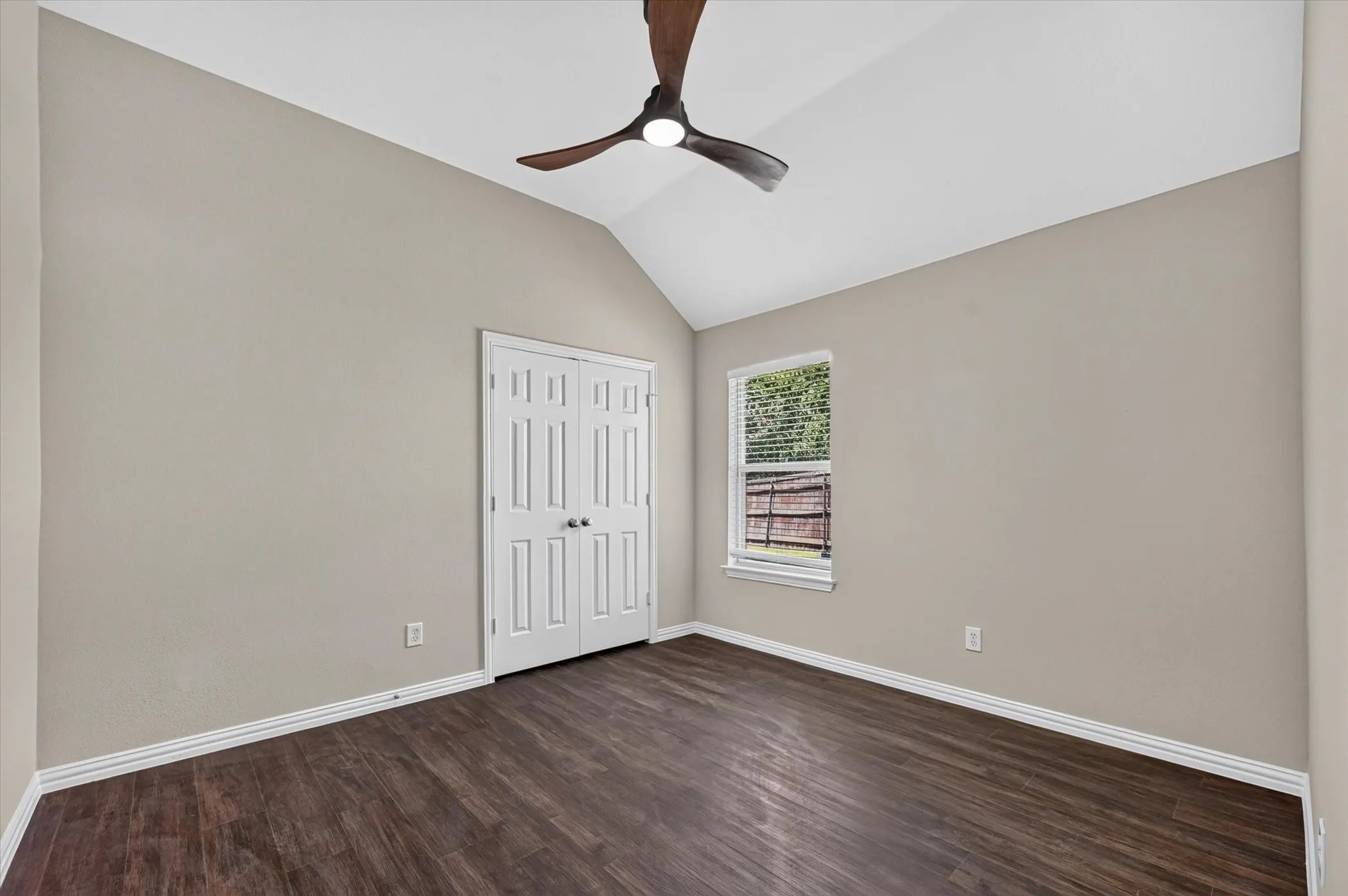 Vaulted ceiling featuring a contemporary ceiling fan, wood-finish flooring, and double panel closet doors