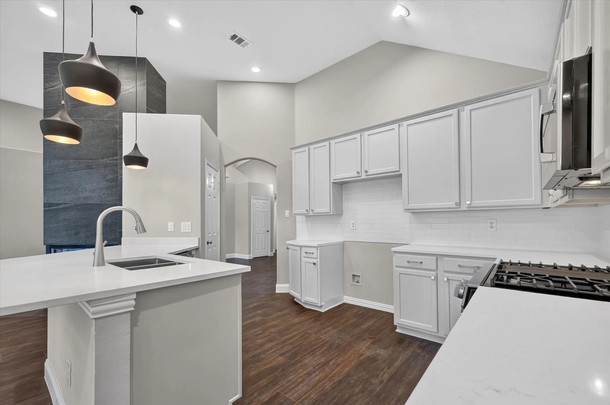Kitchen featuring light-toned cabinetry, a gas range, white countertops, wood-finish flooring, and pendant lighting