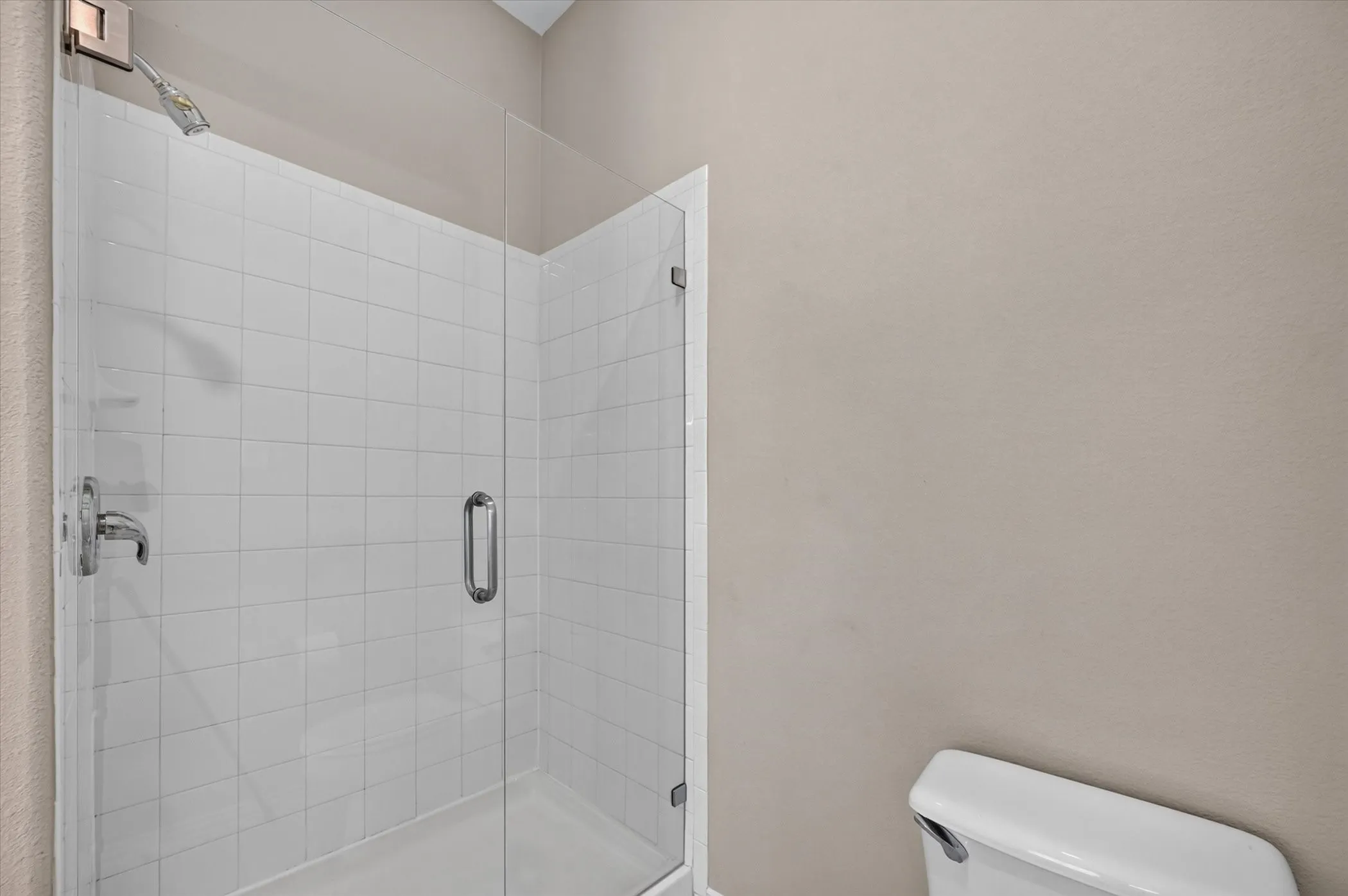 Frameless glass shower enclosure with white tile surround