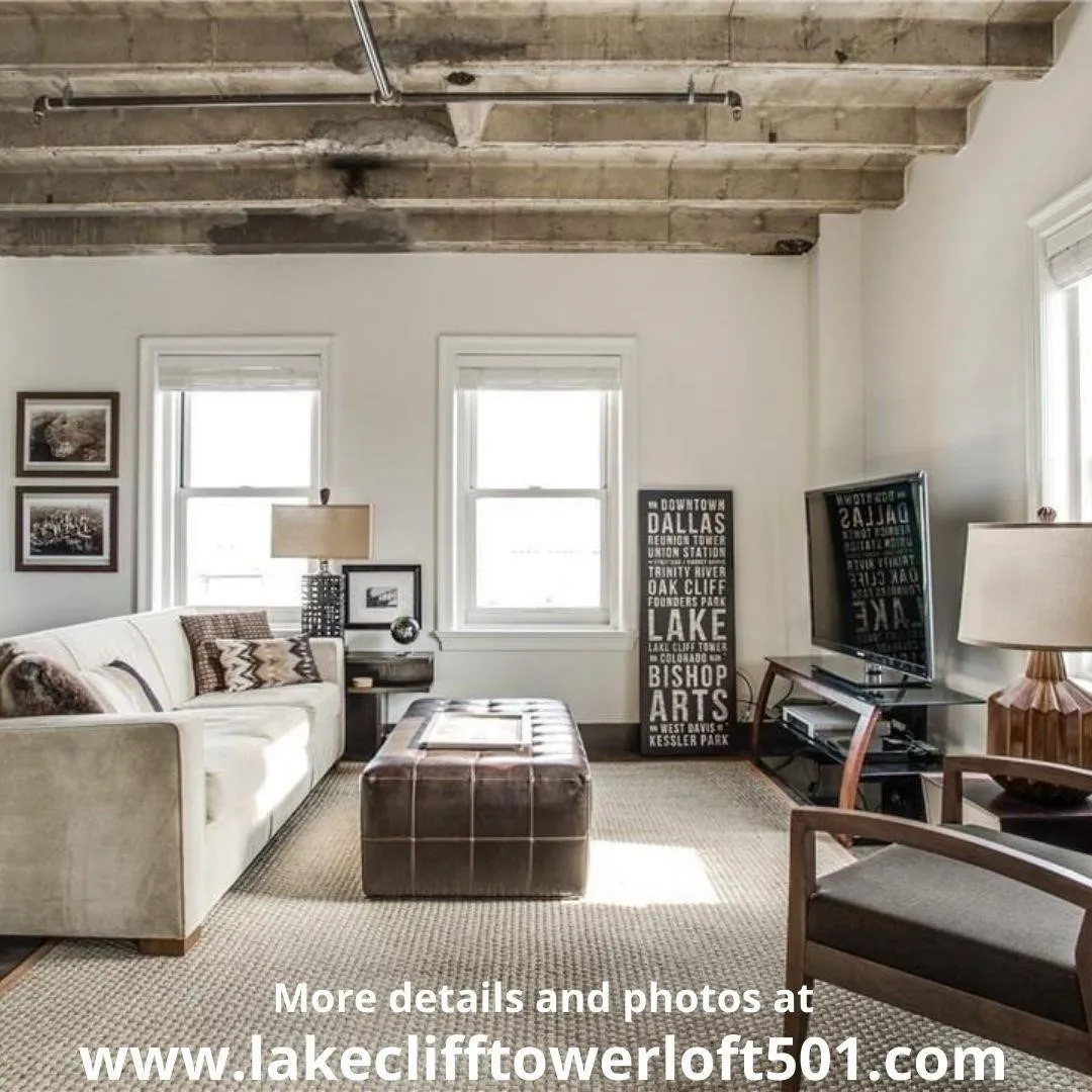 Exposed concrete ceiling beams, multiple windows with natural light, light-toned wall finishes, and carpeted flooring