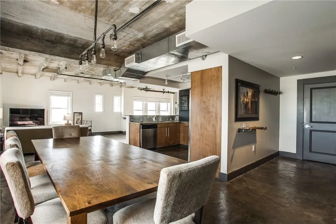 Exposed concrete ceiling, industrial-style track lighting, stained concrete flooring, recessed lighting, and a sliding wood door