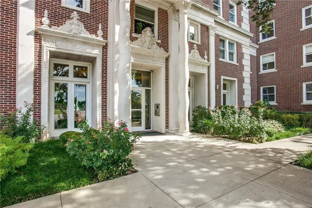 Brick-clad facade featuring ornate stone detailing, grand fluted columns, and double-door entryways