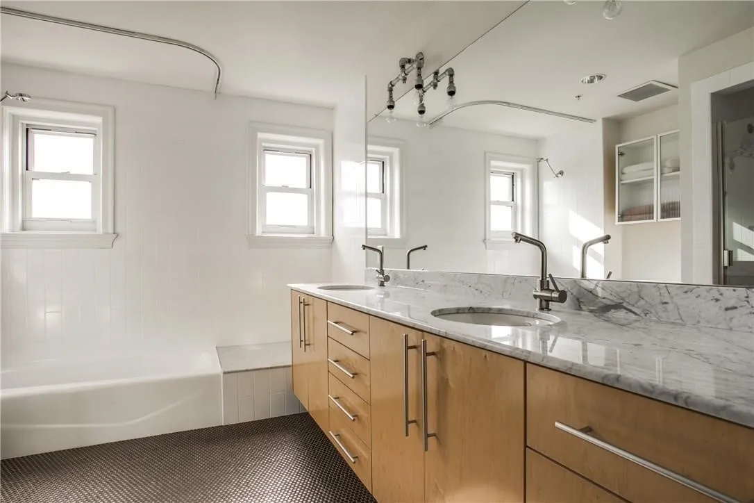 Dual vanity with integrated sinks, light wood-finish cabinetry, and a stone countertop