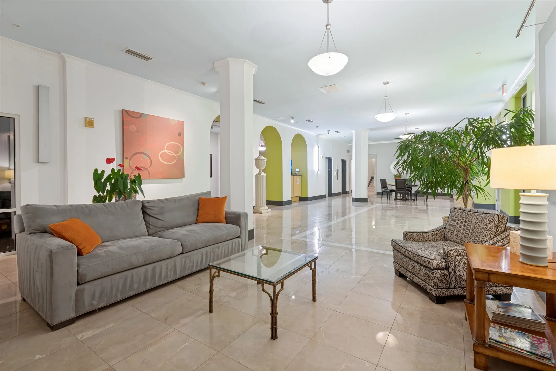Spacious entry hall featuring polished tile flooring, pendant lighting, arched doorways, and recessed wall lighting