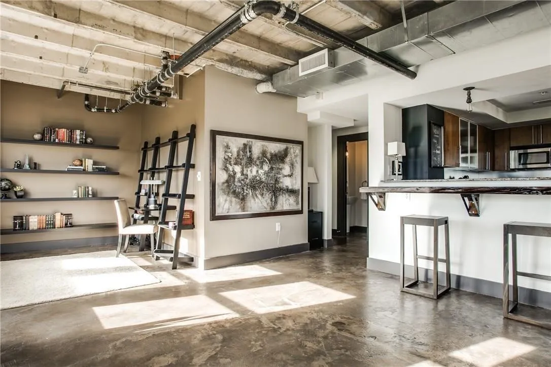 Exposed concrete ceiling, industrial-style ductwork, concrete flooring, built-in shelving, and a bar-height counter