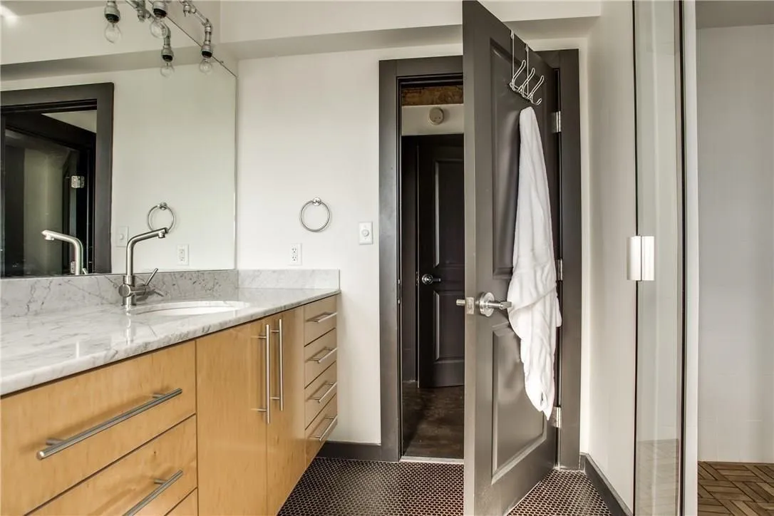 Vanity with a polished stone countertop, undermount sink, and wood-finish cabinetry with brushed nickel hardware