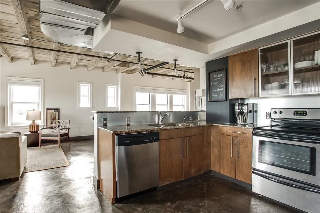 Kitchen featuring stainless steel appliances, wood-finish cabinetry, and granite countertops