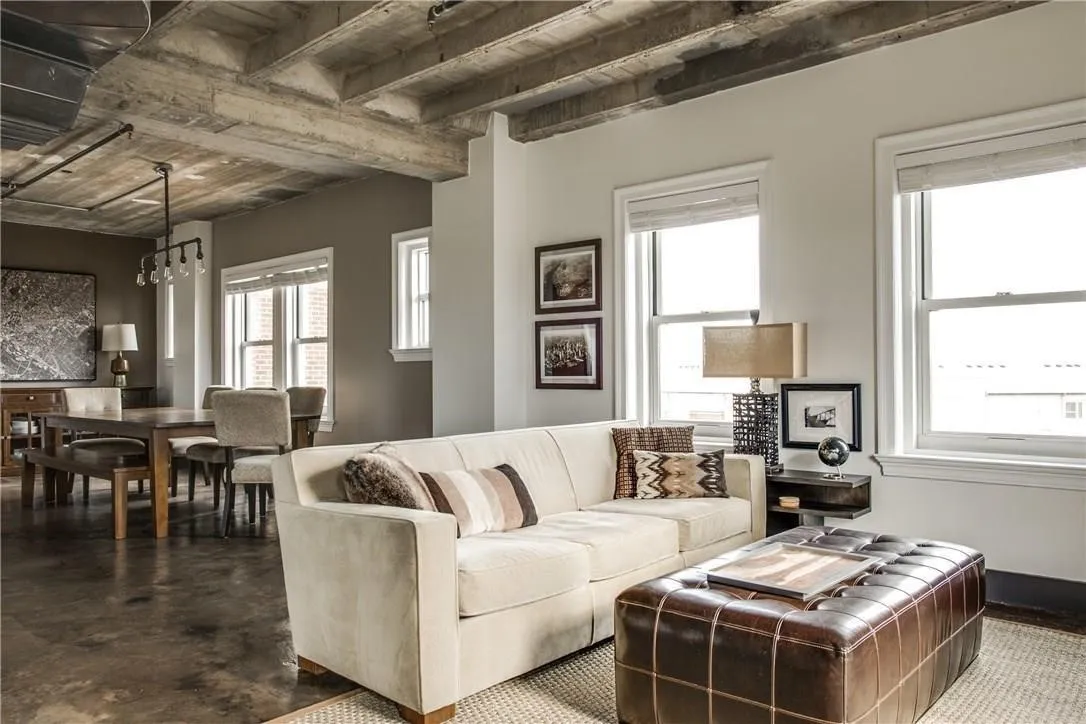 Exposed concrete ceiling with beam details, light-toned walls, multiple large windows, and a built-in wall niche