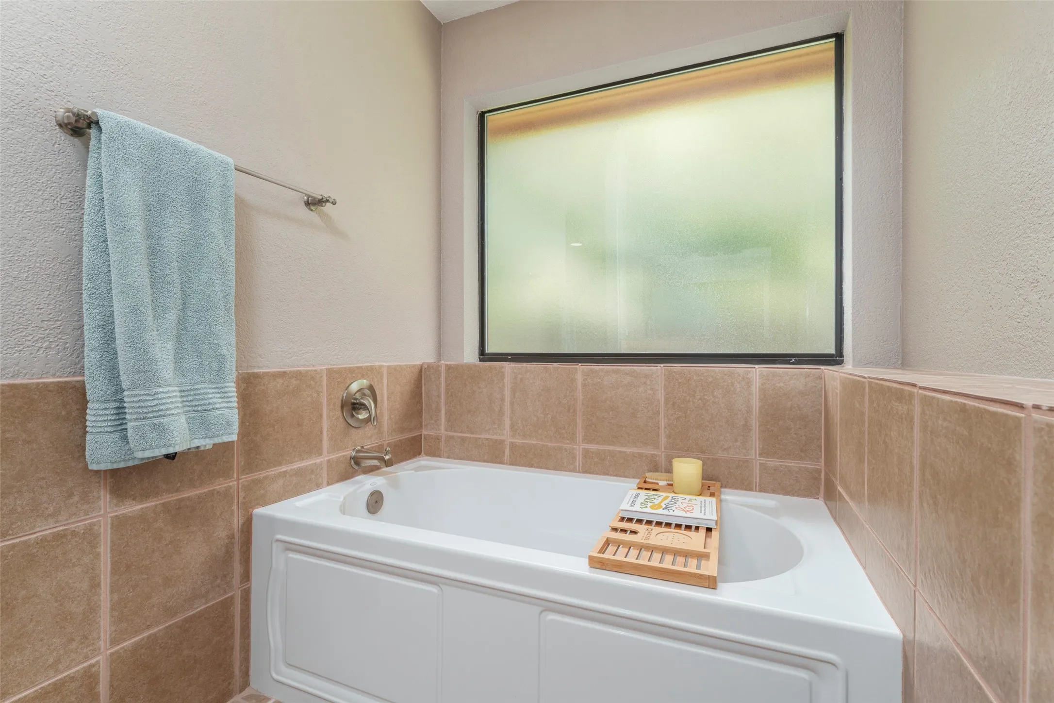 Jacuzzi walk in shower and bathtub with tiled surround, brushed nickel fixtures, and a frosted window