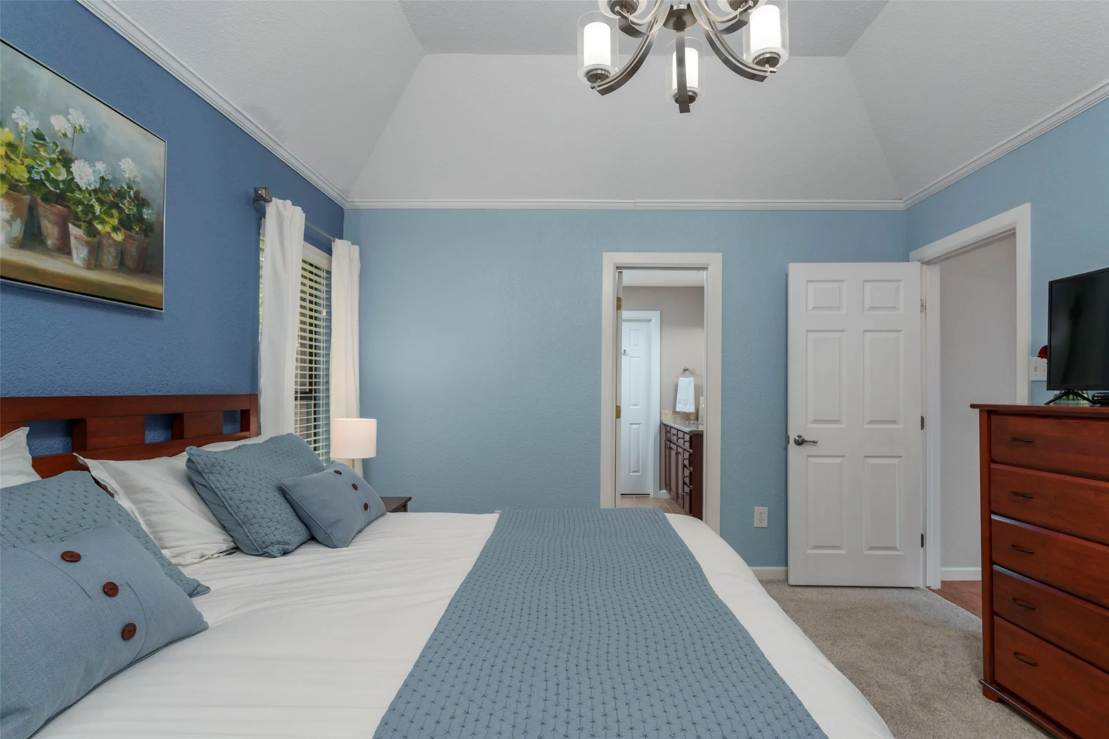 Vaulted ceiling with a chandelier, crown molding, and wall-to-wall carpeting
