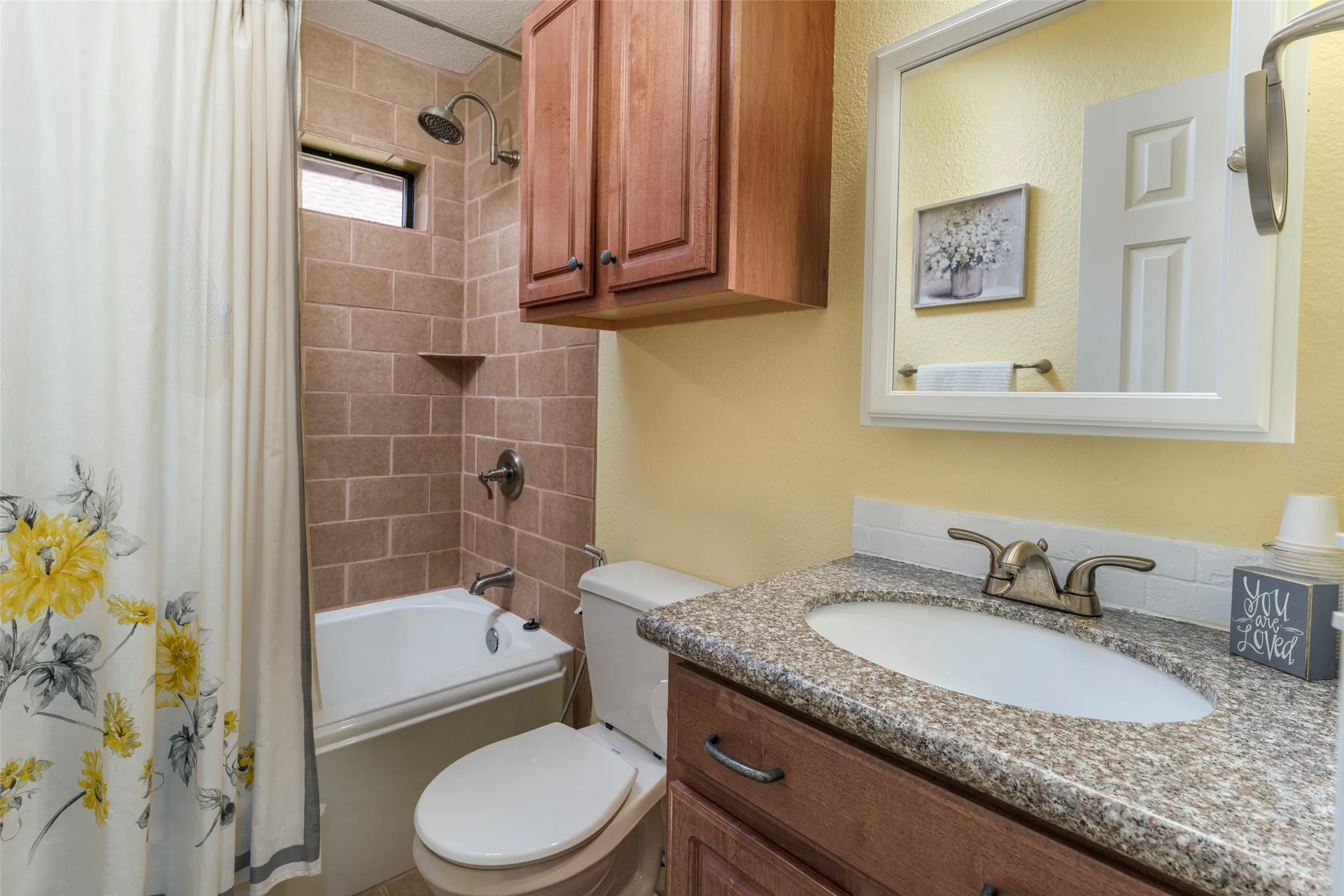 Bathroom featuring a vanity with an integrated sink, granite-style countertop, and wood-finish cabinetry