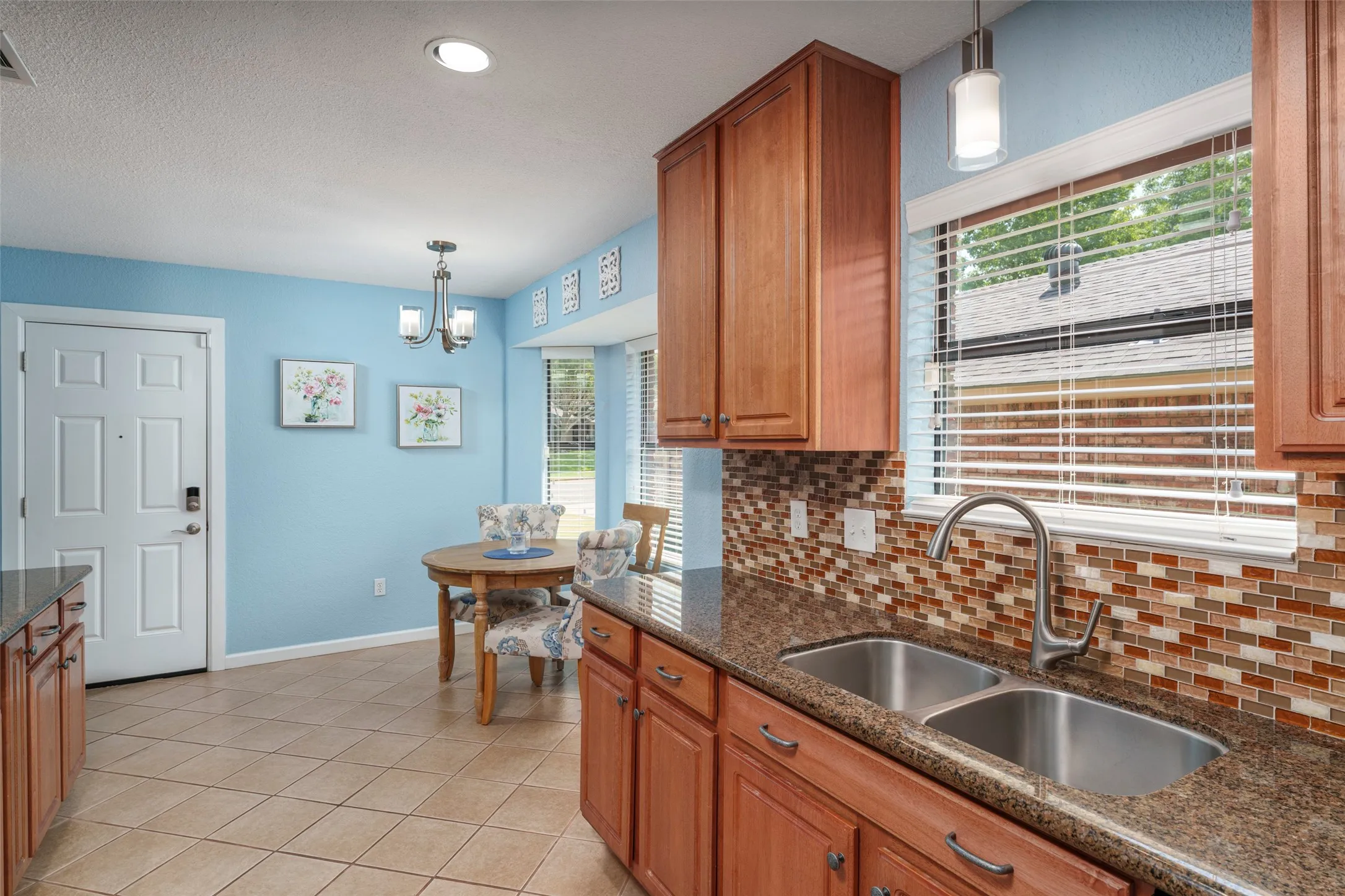 Kitchen with wood-finish cabinetry, granite-style countertops, and a mosaic tile backsplash.Motion Sensor faucet
