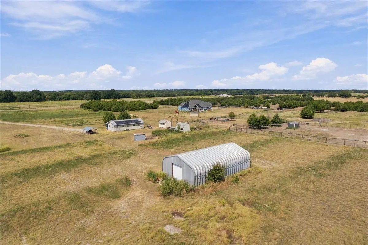 Back view of home, chicken coop, yellow storage bldg; old barn, metal shop