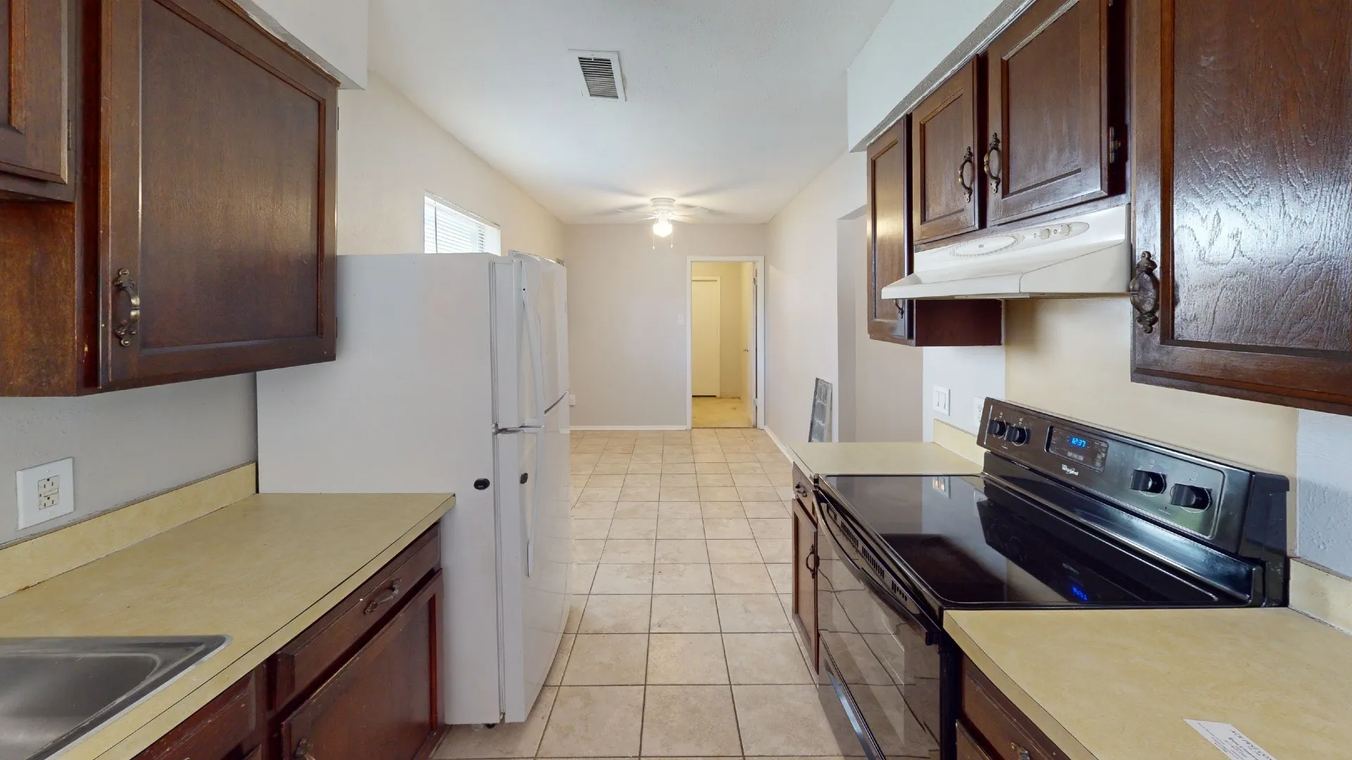 Kitchen featuring wood-finish cabinetry, light-toned countertops, and tile flooring