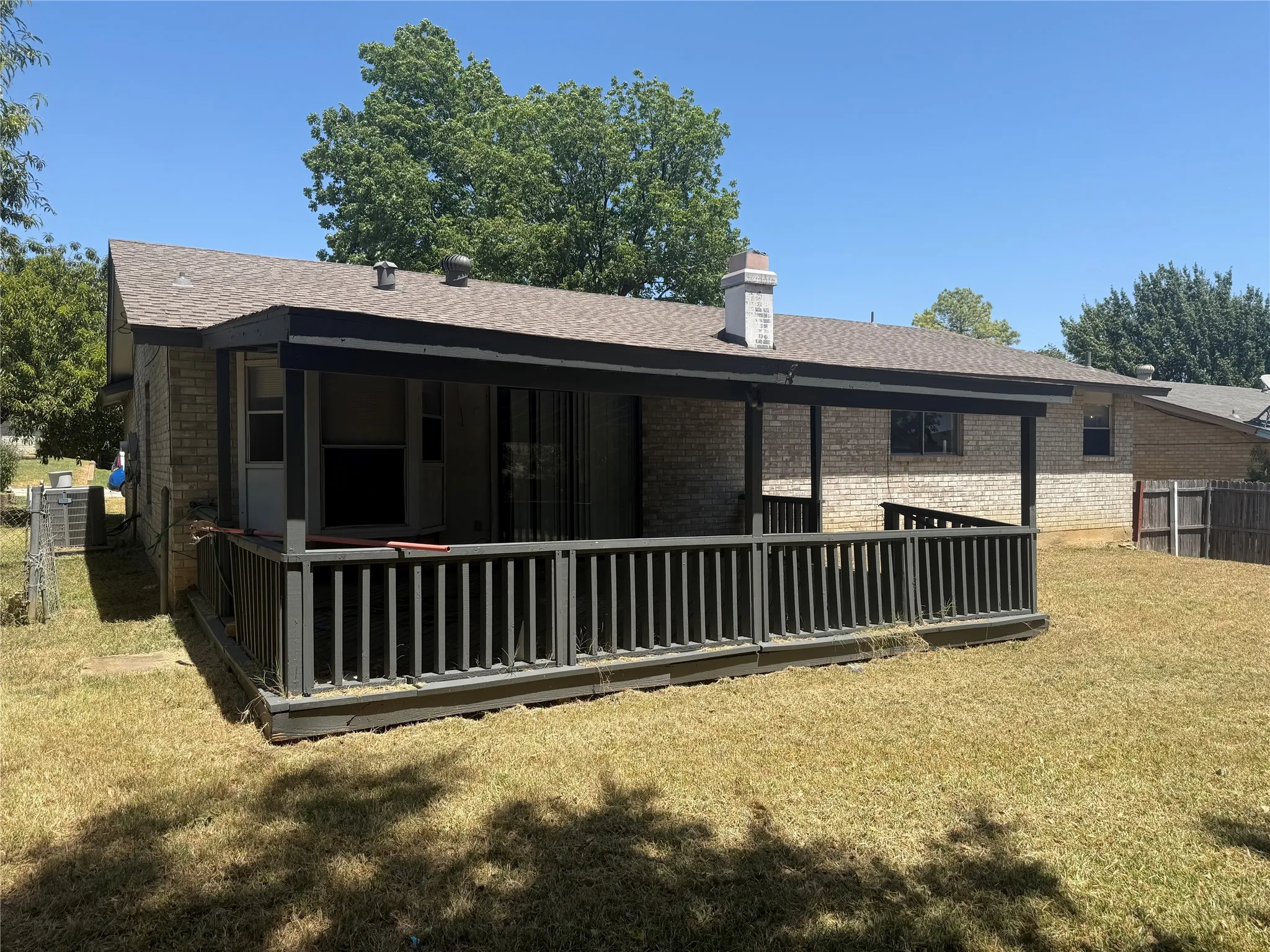 Brick exterior with a covered patio and wood railing