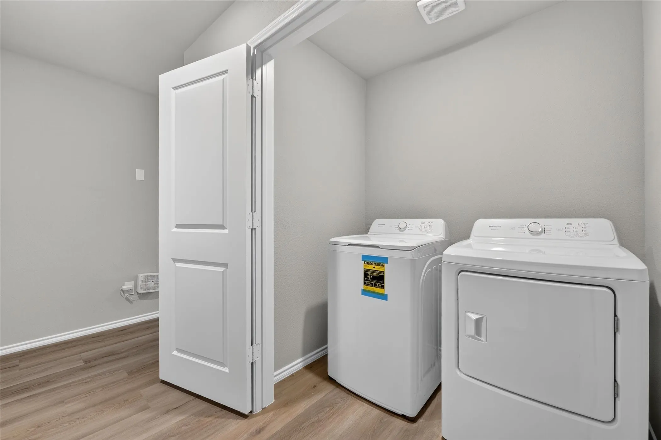 Dedicated laundry area featuring a washer and dryer, light gray walls, and wood-finish flooring
