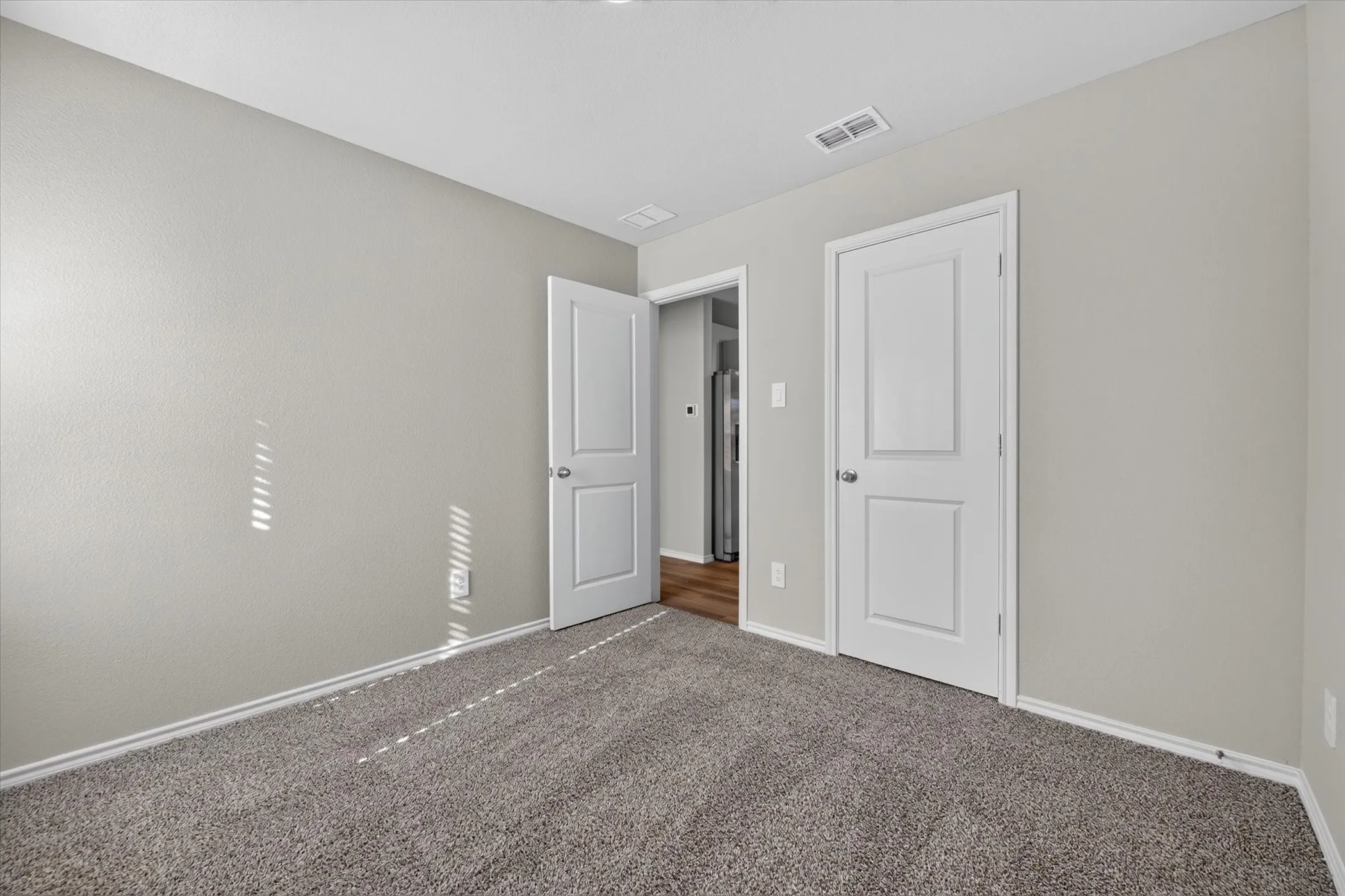 Neutral wall paint, gray carpeting, white trim, and white paneled doors