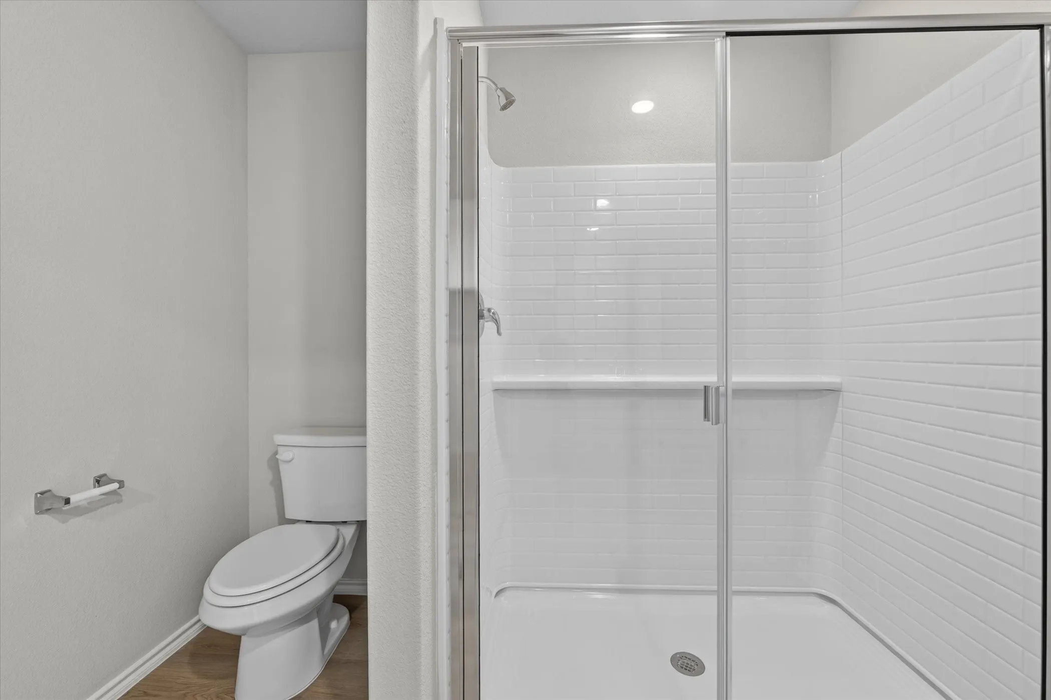 Shower with subway tile surround, clear glass enclosure, and recessed lighting