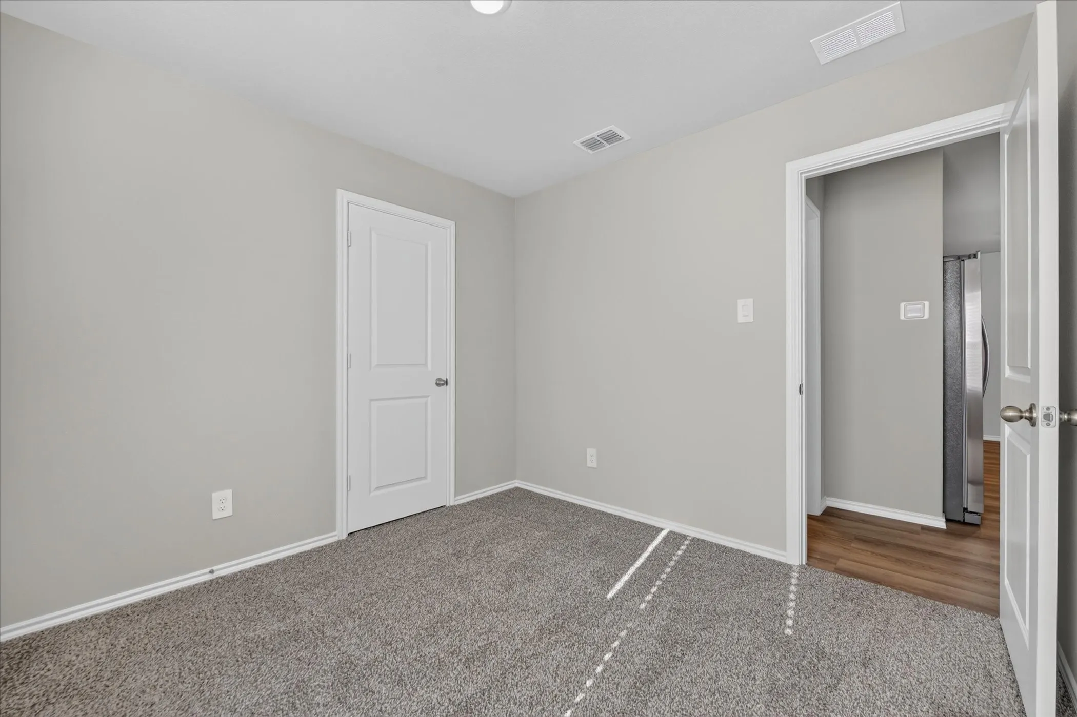 Neutral tone wall paint, textured carpeting, white trim, and two-panel interior doors
