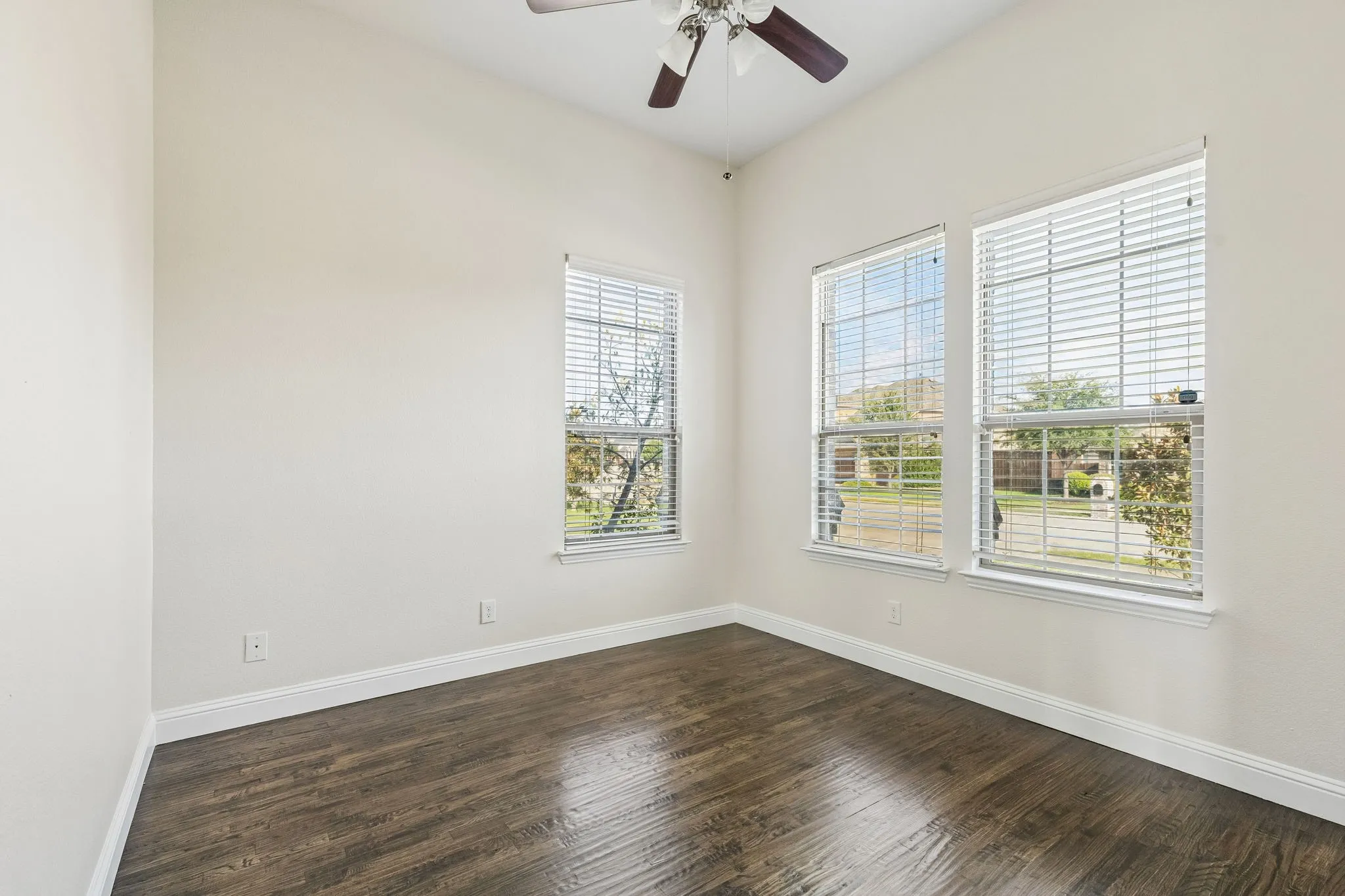 Vaulted ceiling with a ceiling fan, dual windows with blinds, and wood-finish flooring