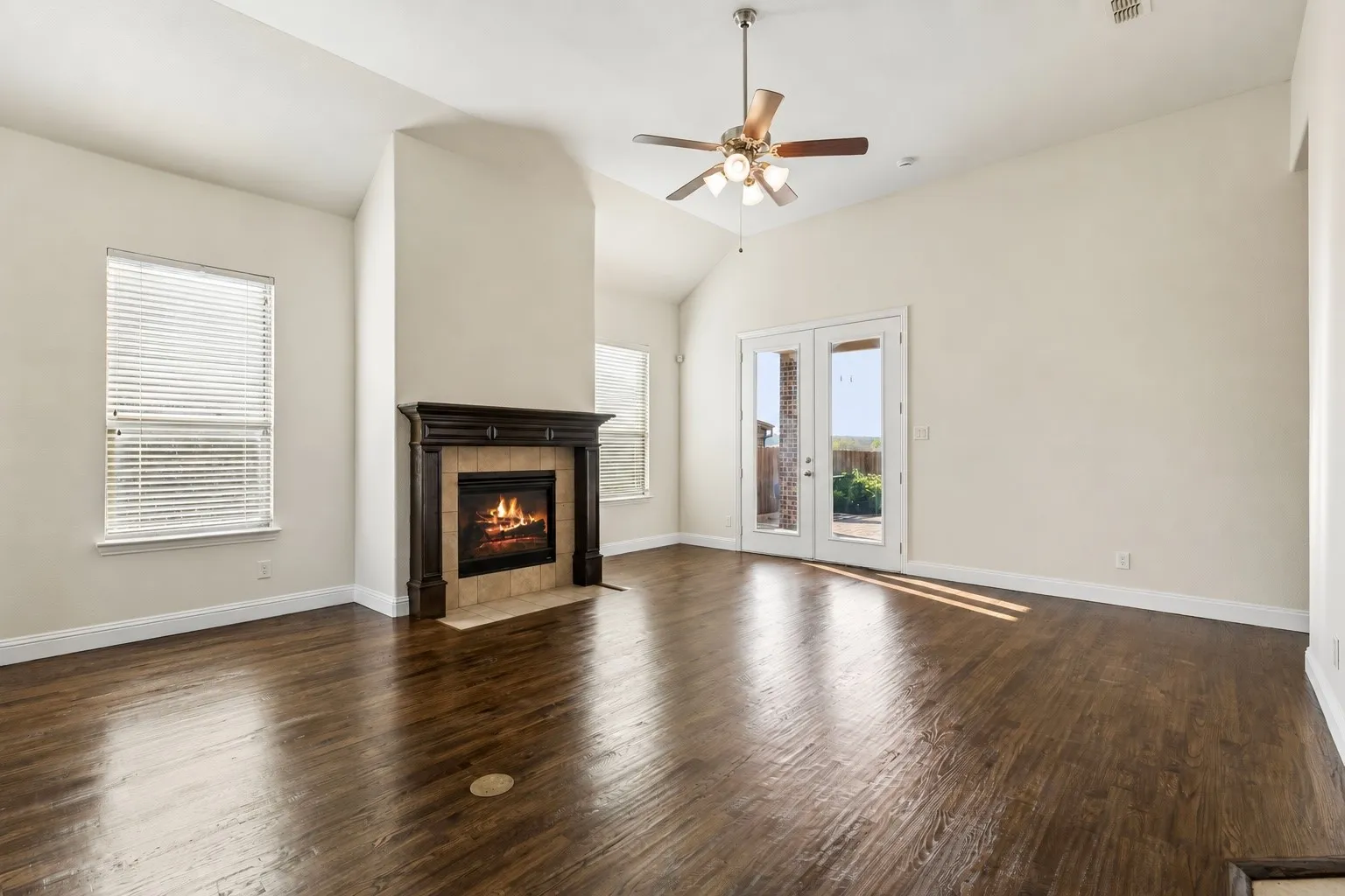 Vaulted ceilings, wood-finish flooring, and a fireplace with a decorative mantel
