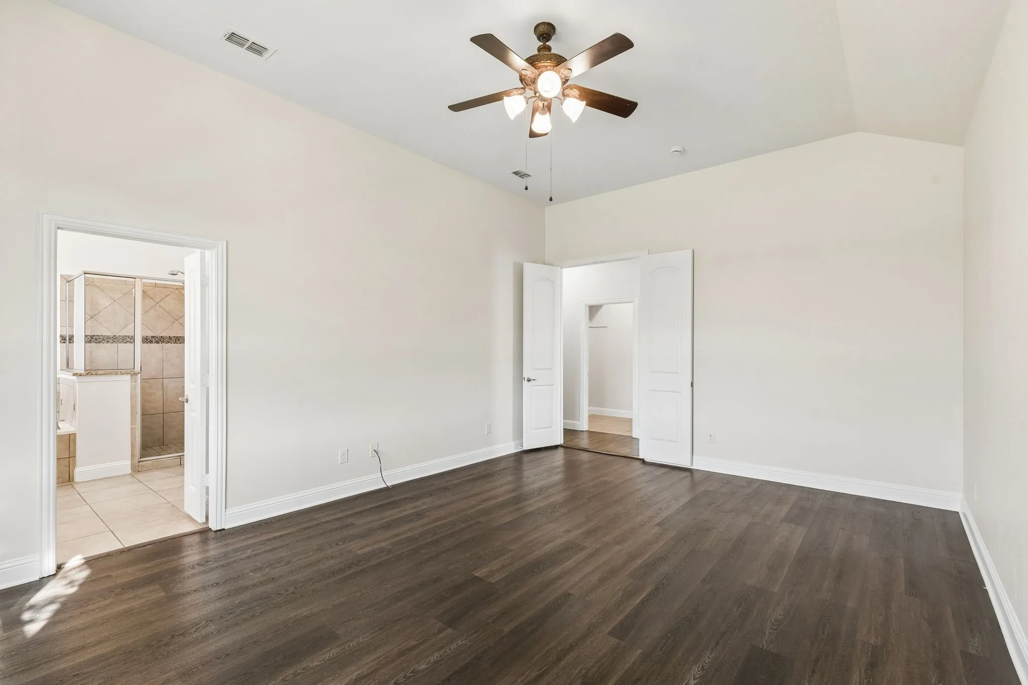 Vaulted ceiling with a ceiling fan, wood-finish flooring, and crisp white walls