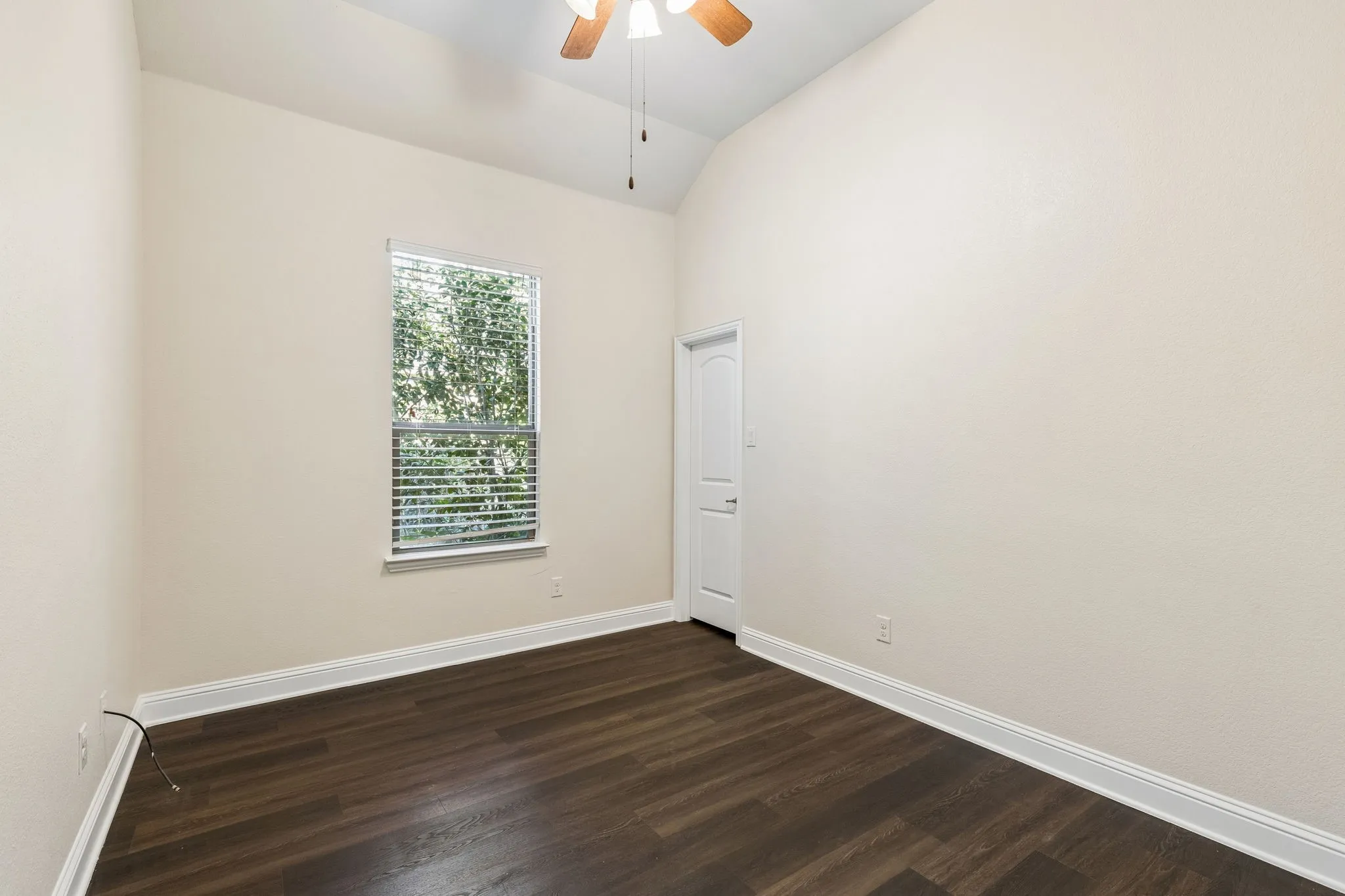 Vaulted ceiling with an attached ceiling fan, wood-finish flooring, and a single window with blinds