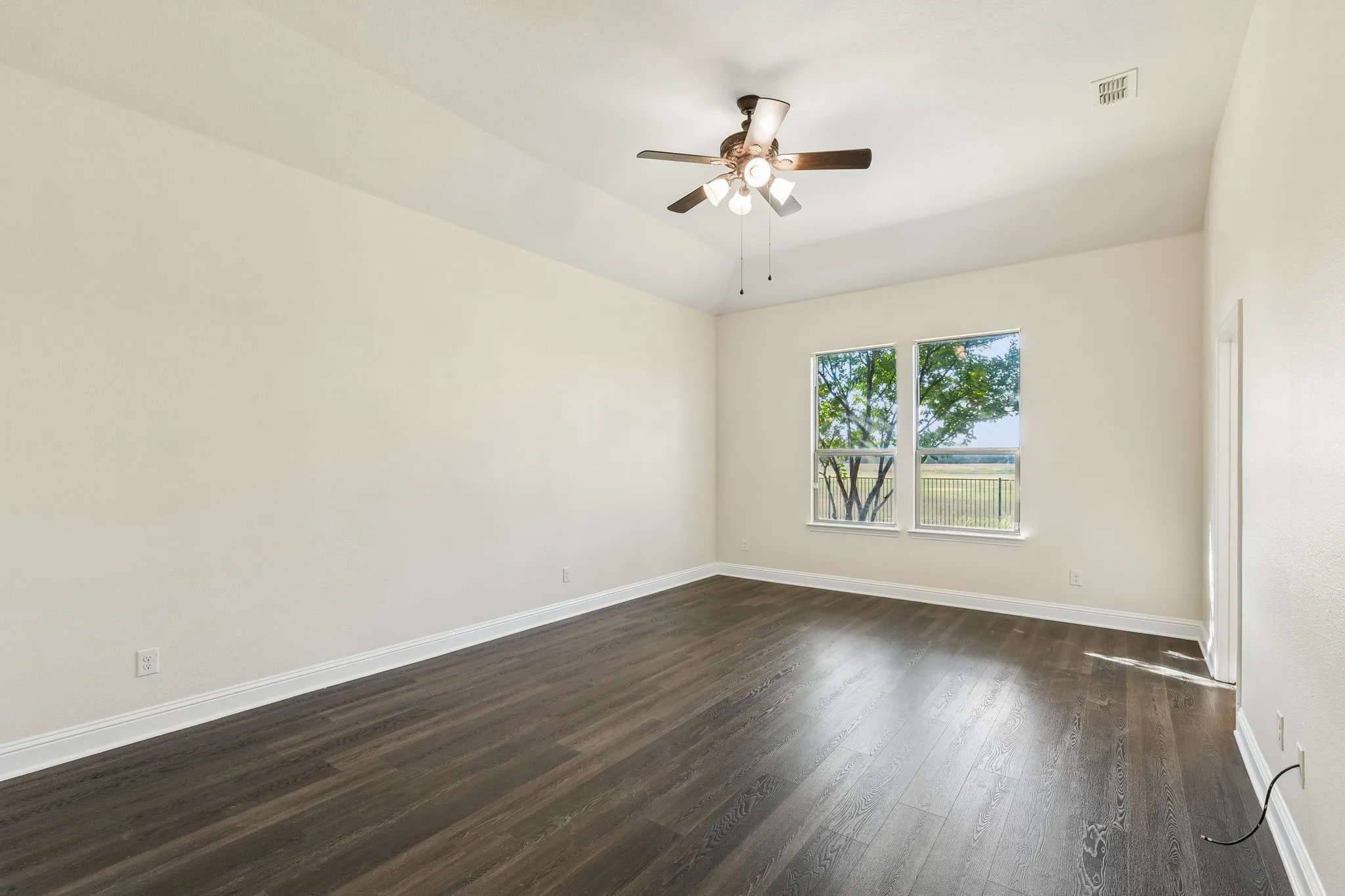 Spacious room featuring wood-finish flooring and two windows