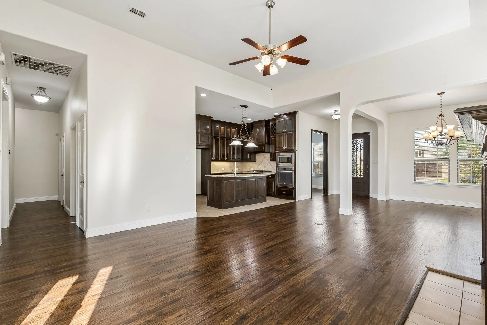 Hardwood-style flooring throughout, an arched entryway, recessed lighting, and a ceiling fan with light fixture