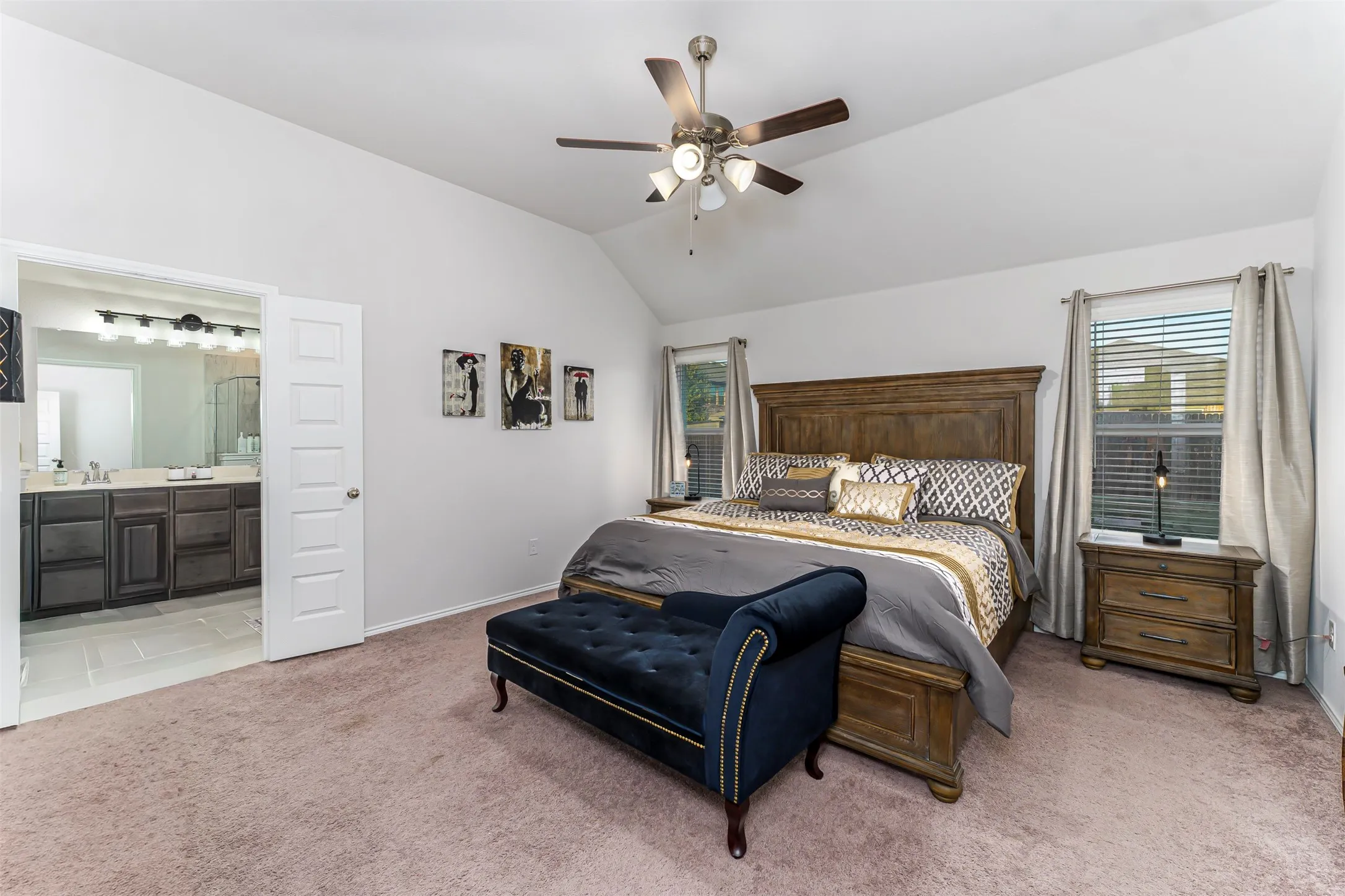 Vaulted ceiling with a ceiling fan, carpeted flooring, two windows with blinds, and a five-panel interior door