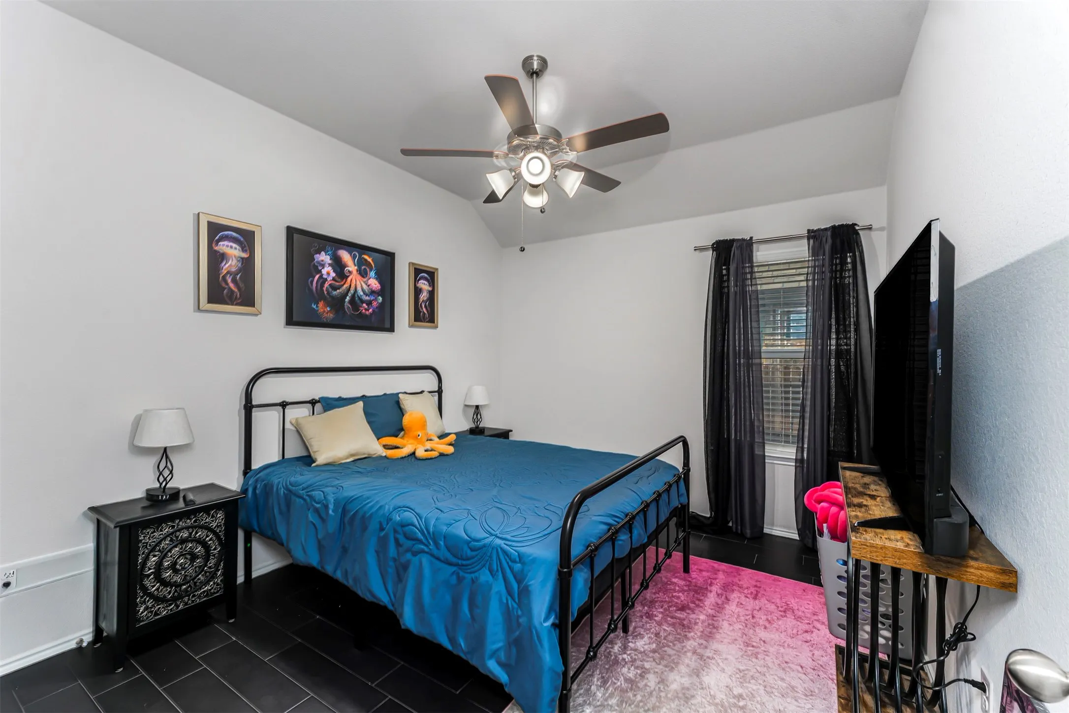 Vaulted ceiling with a ceiling fan, black tile flooring, and a large window with blinds