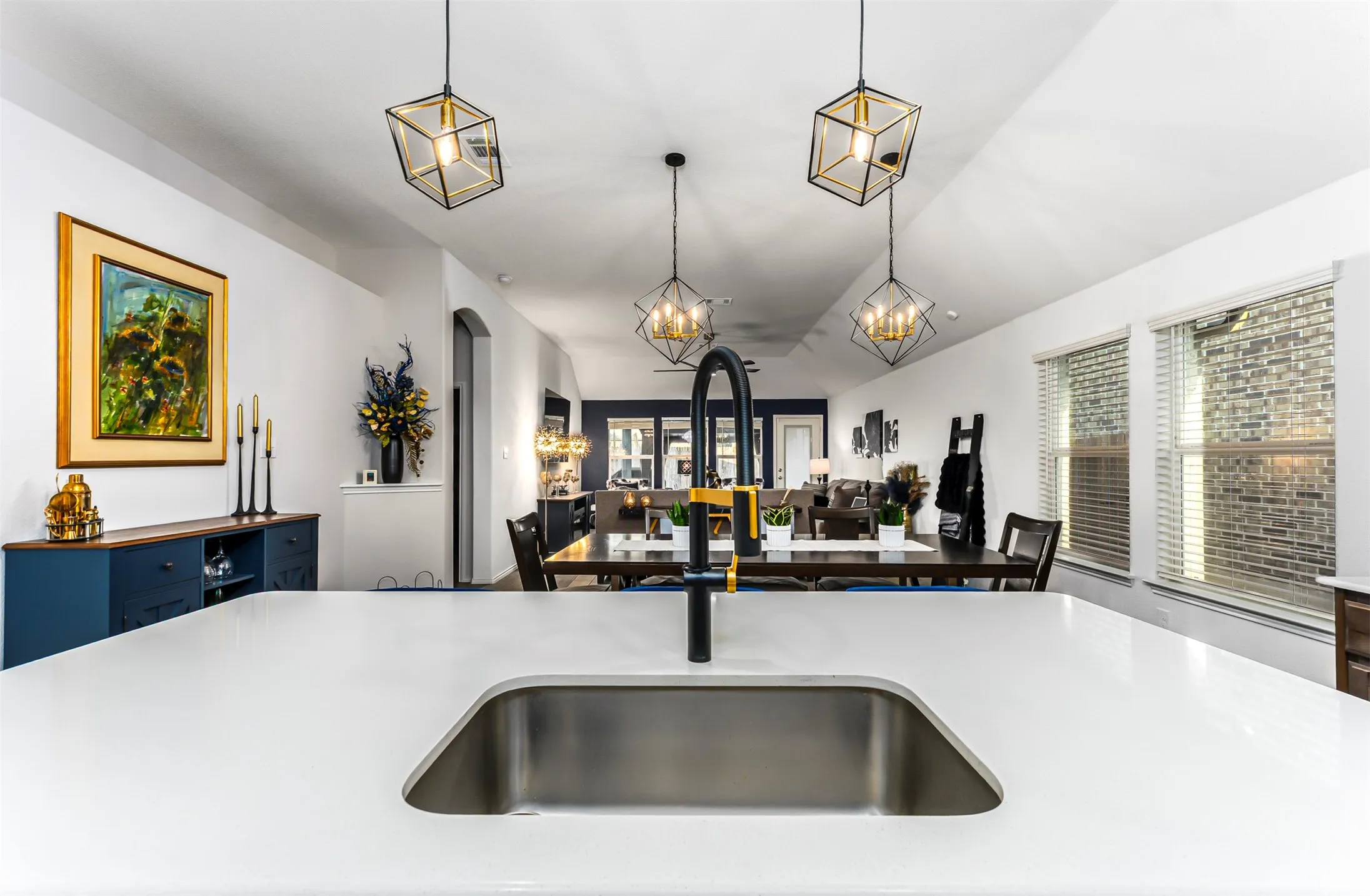Kitchen island with an undermount stainless steel sink, a matte black and gold-tone faucet, and white countertops