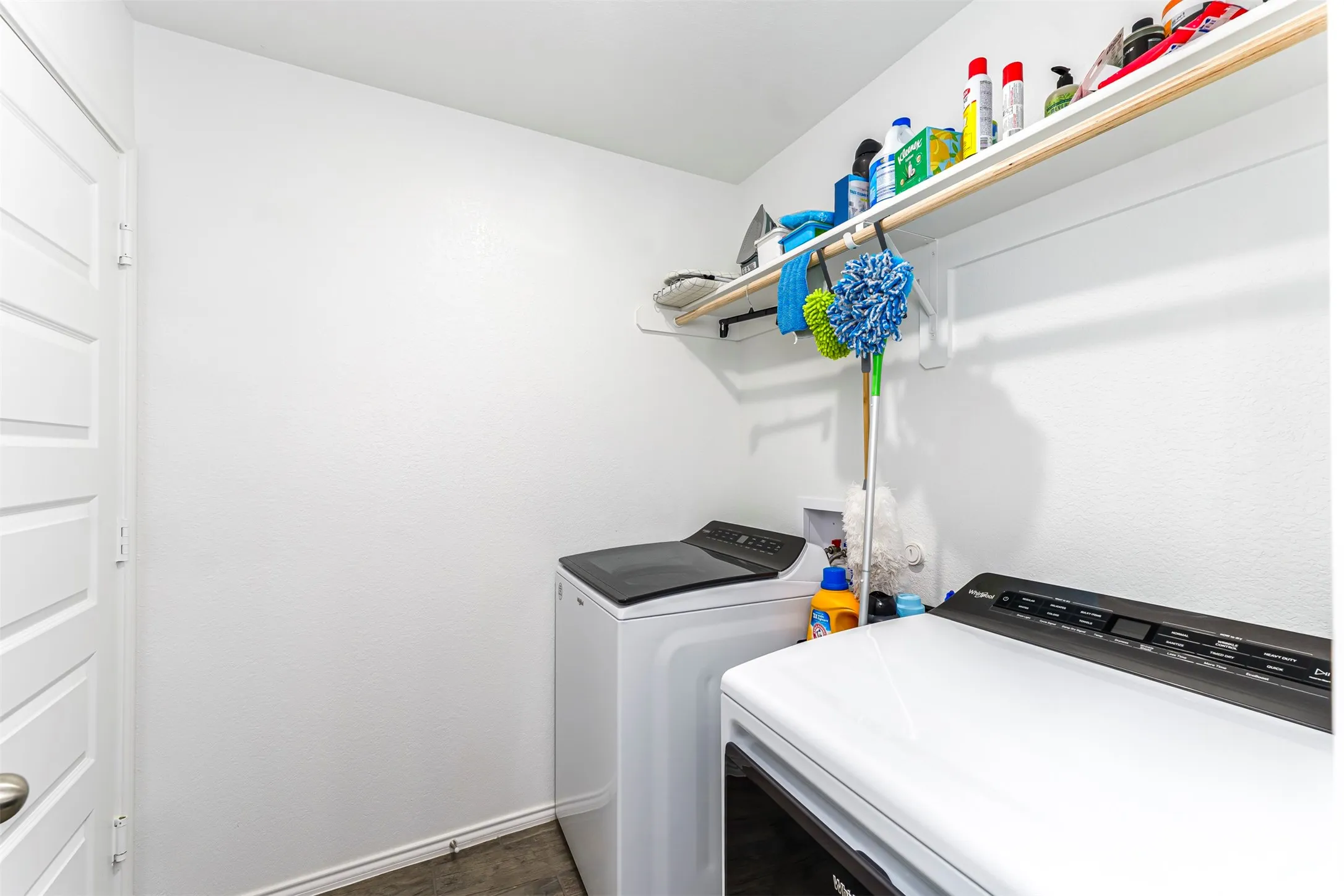 Dedicated laundry area with upper shelving and a clothing rod