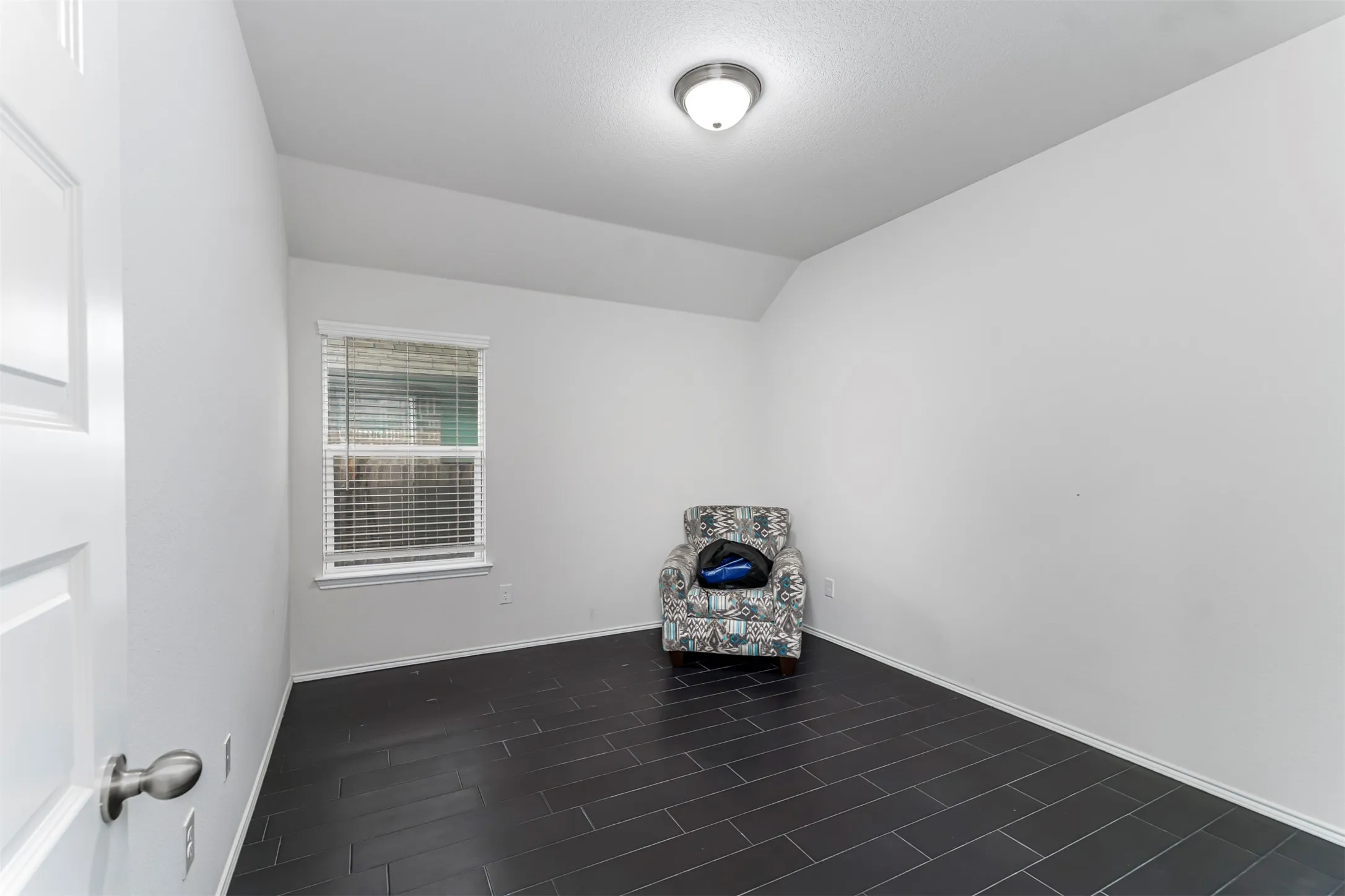 Dark tile flooring, white walls, and a single window with blinds