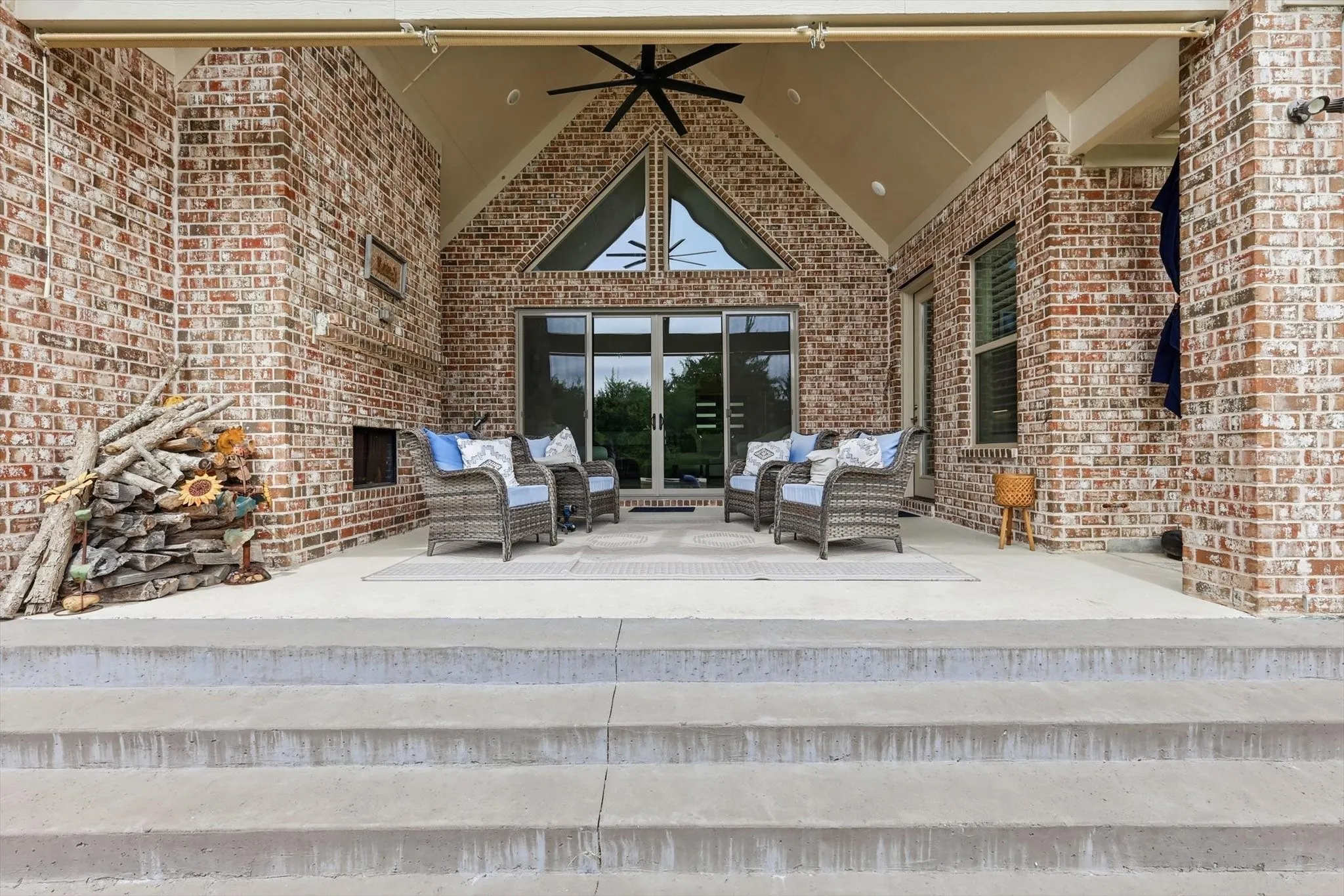 Brick exterior patio featuring a vaulted ceiling, ceiling fan, and sliding glass doors