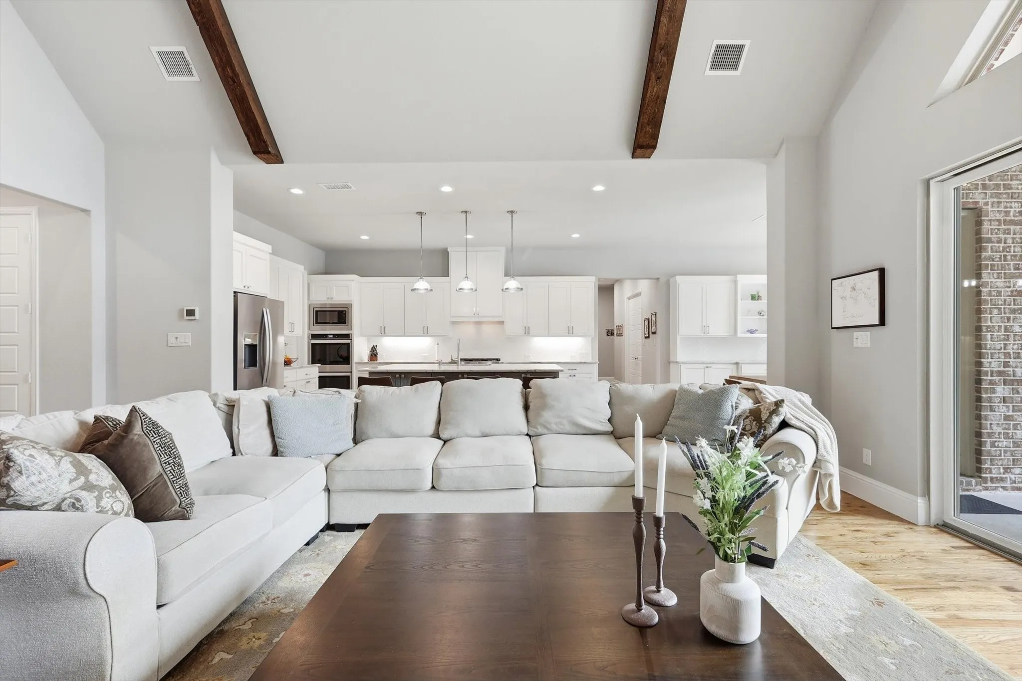 Living area with vaulted ceilings, exposed wood beams, and wood-finish flooring