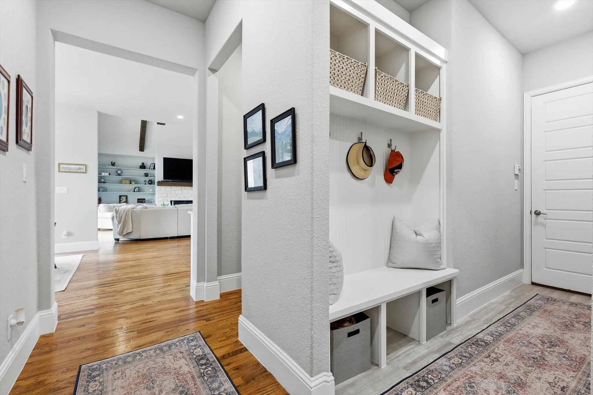 Built-in hall tree with integrated storage, wood-finish flooring, white panel door, recessed lighting, and crisp wall finishes