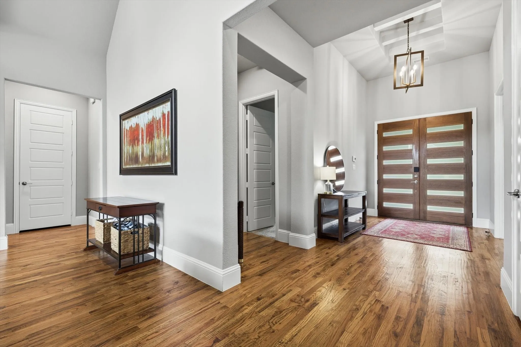 Warm wood flooring throughout, complemented by a contemporary chandelier